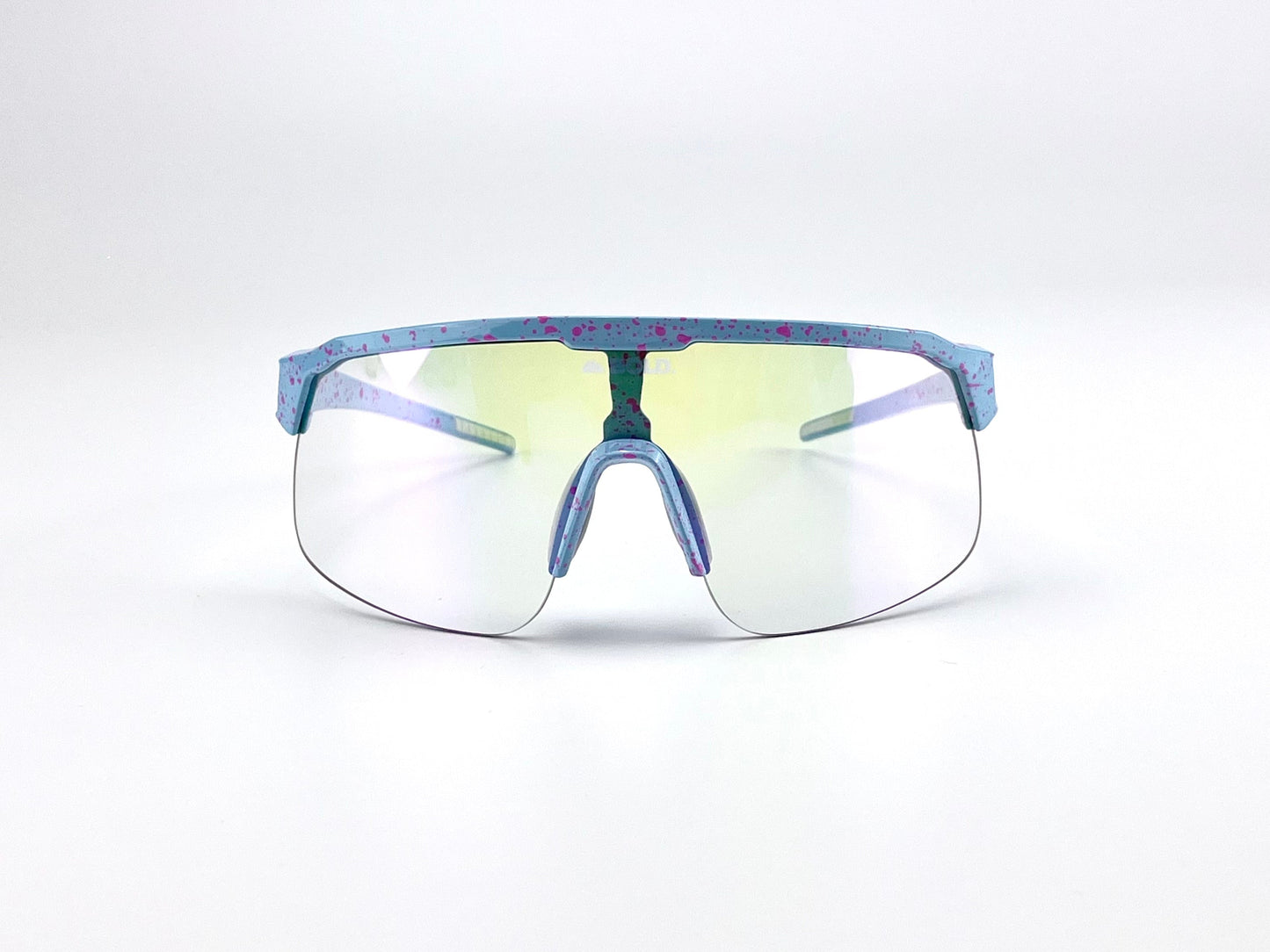 The BOLD Zippy Photochromic Sunglasses by boldouterwear feature a futuristic, lightweight design with a single curved tinted lens and a blue frame speckled with pink spots, plus matching nose pads and arms—perfect for MTB, ski, and lifestyle use.
