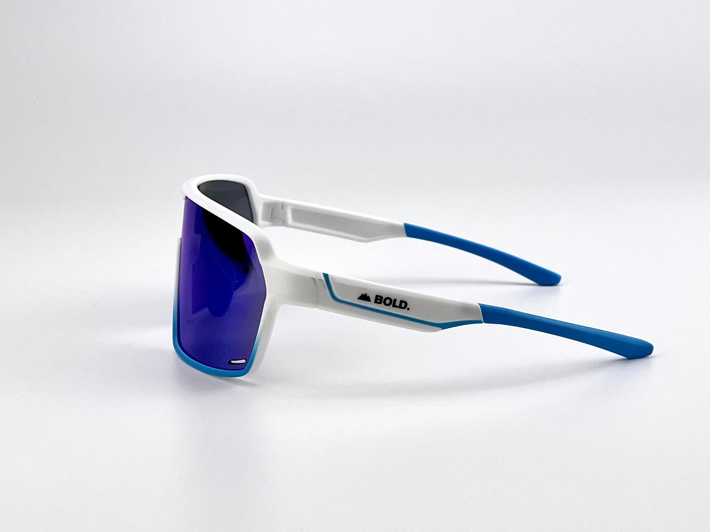BOLD Shadows Performance Sunglasses by boldouterwear feature a white and blue frame, blue-tinted wraparound lenses, and blue earpieces. "BOLD." is printed in black on the side arm. Displayed against a plain white background.