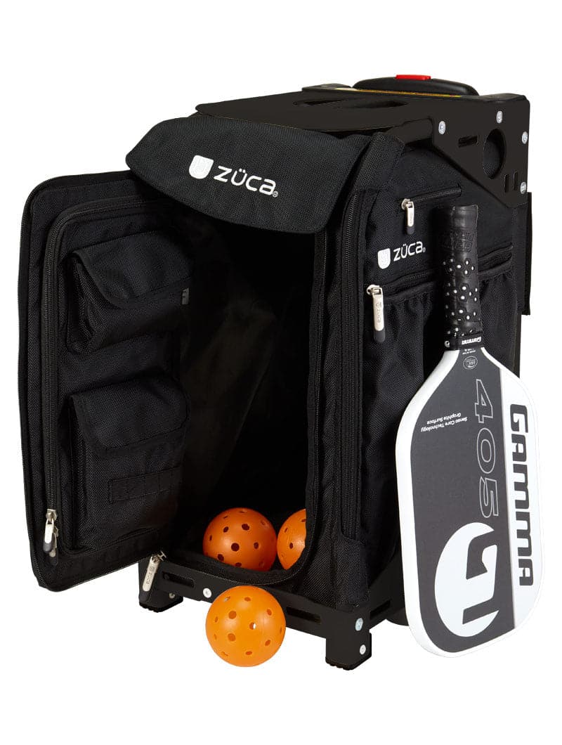The ZUCA Pickleball Pro Black/Black bag features an open front displaying orange pickleballs, zippered storage pockets, and a white and black Gamma paddle at its side—ideal for organized pickleball gear storage on a white background.