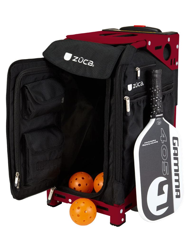 A ZUCA Pickleball Pro Black/Black rolling bag with open front and side zippered compartments holds three orange pickleballs inside. A black pickleball paddle fits in the mesh side pocket, keeping your gear organized for every match.