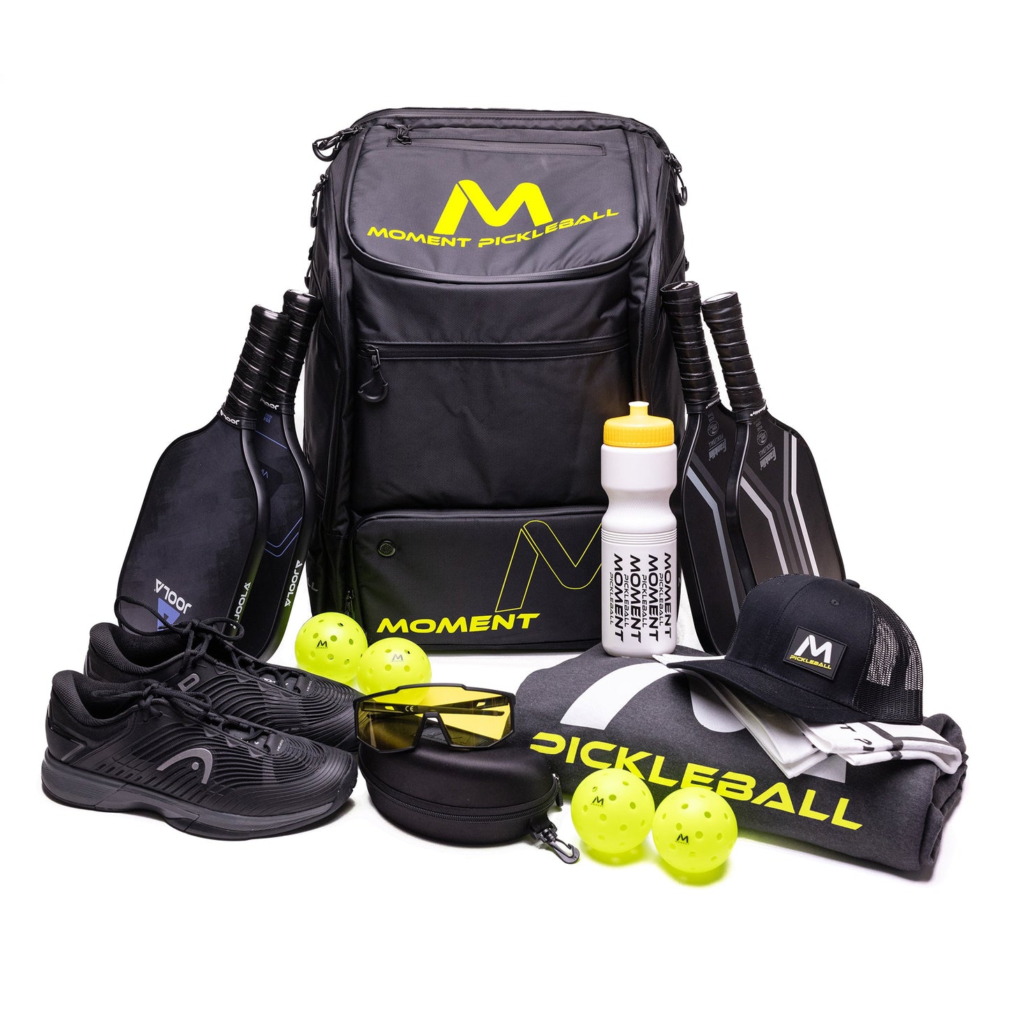 The MW-PRO Bag / Travel Bag Black/Yellow by Moment Pickleball is surrounded by top pickleball gear: two black paddles, four yellow balls, black shoes, a water bottle, cap, shirt, sunglasses case, and gray towel.