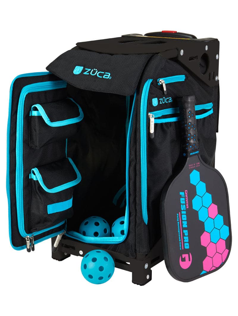 A ZUCA Pickleball Pro Black/Blue rolling bag is open, showing several storage compartments with three yellow balls inside and one on the floor. A black and blue “FUSION PRO” paddle is attached to the front.