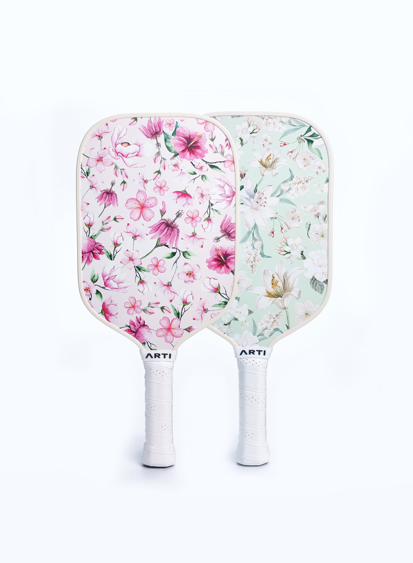 The ARTI Fiberglass "Flowers" Pickleball Paddle Set features two USAPA-approved paddles: one with a pink floral design, the other with a greenish background and white/yellow flowers—both with white grips for a soft, elegant touch.