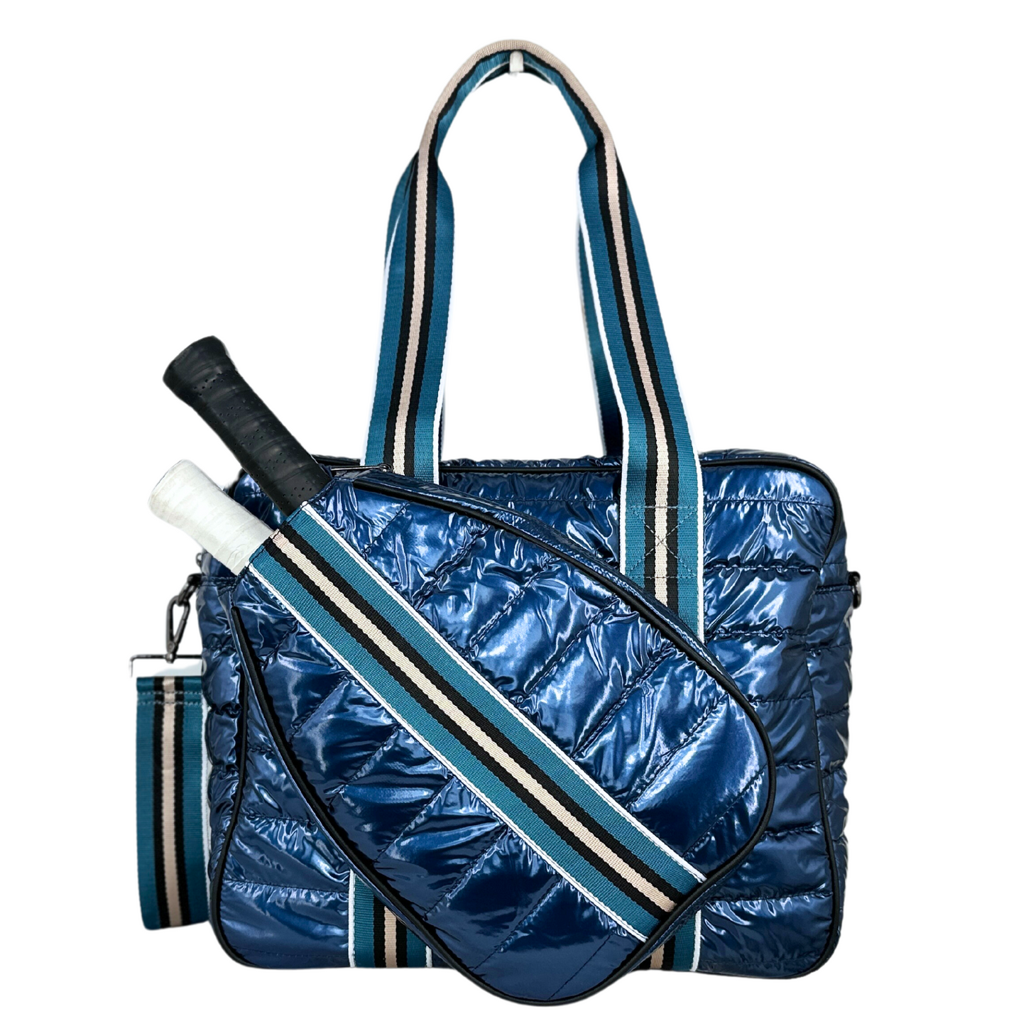 The Queen of the Court Kelsey Pickleball Bag features shiny blue quilted material, black, white, and blue striped handles and strap, a matching side pocket for two rackets with black and white grips, and a sporty, stylish design.