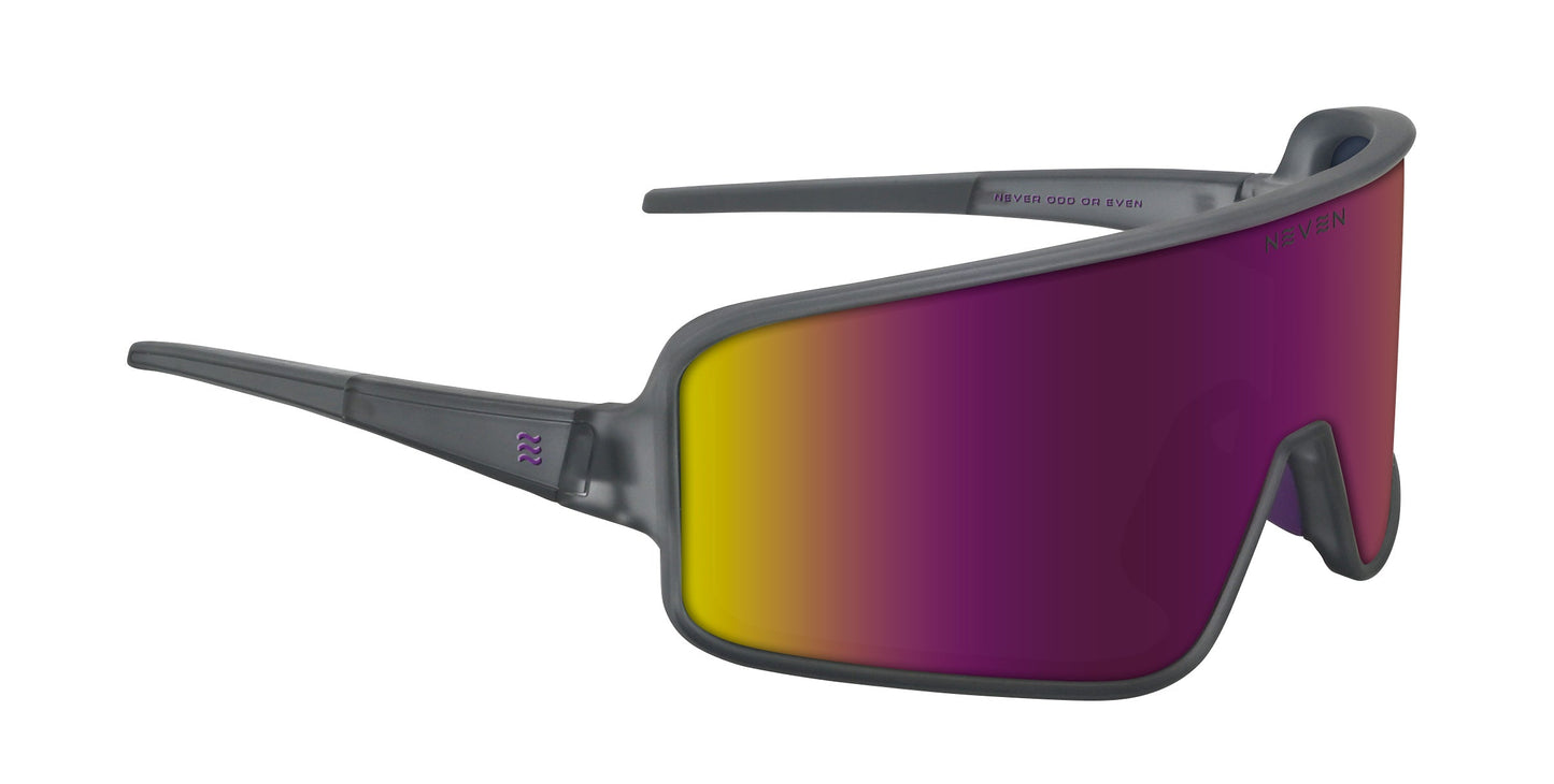 The Mattingly by Neven Eyewear features oversized wraparound sunglasses with a thick gray frame and wide temples. A single shield lens fades from yellow to purple, evoking vintage baseball style, with subtle branding on the frame and lens.