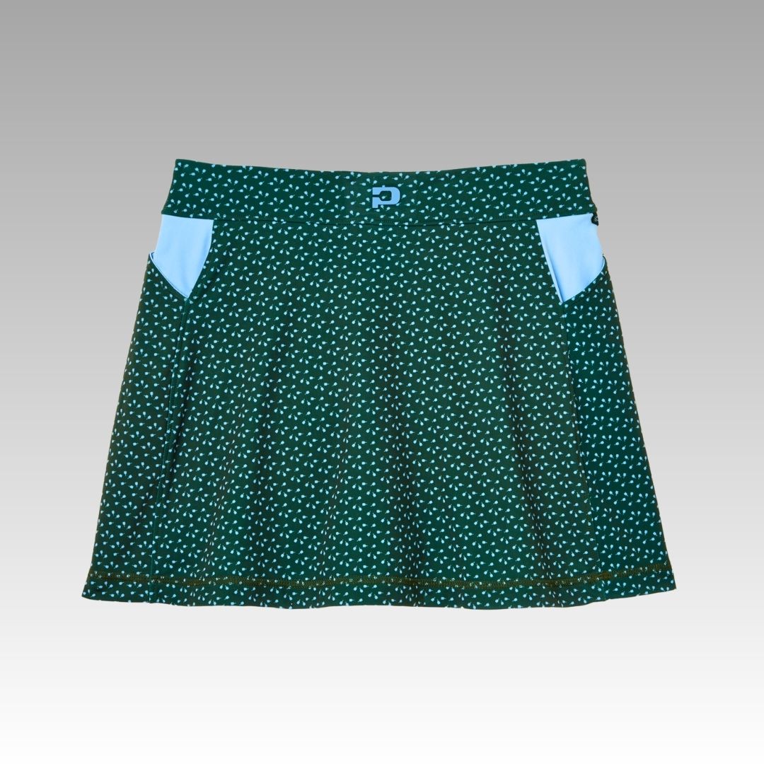 The Sammy Skort by Playly Store is a dark green A-line pickleball skort in SofKnit fabric, featuring a white dotted pattern, two light blue pockets, and a simple waistband. Displayed on a neutral gray gradient background. Moisture-wicking and slightly flared.