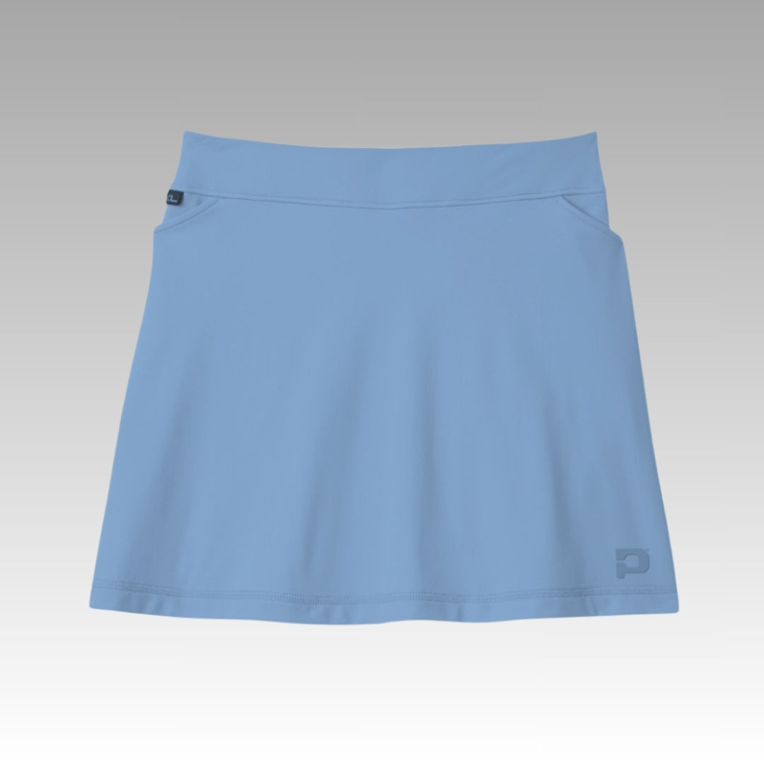 The Playly Store Sammy Skort 2.0 in light blue, made with CoolFlow fabric, is shown on a gradient gray-to-white background. It has a wide waistband, side pockets, a small logo near the hem, and features a simple, minimalistic design.