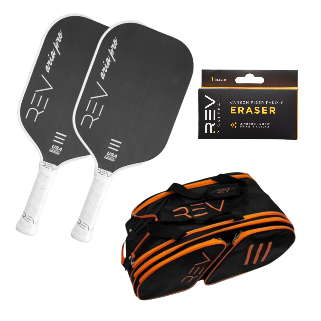 The REV Pickleball Professional - Mix & Match - Bundle for 2 includes two black paddles with white grips, a black and orange sports bag with orange zippers, and a Carbon Fiber Paddle Eraser, all branded with the REV logo.