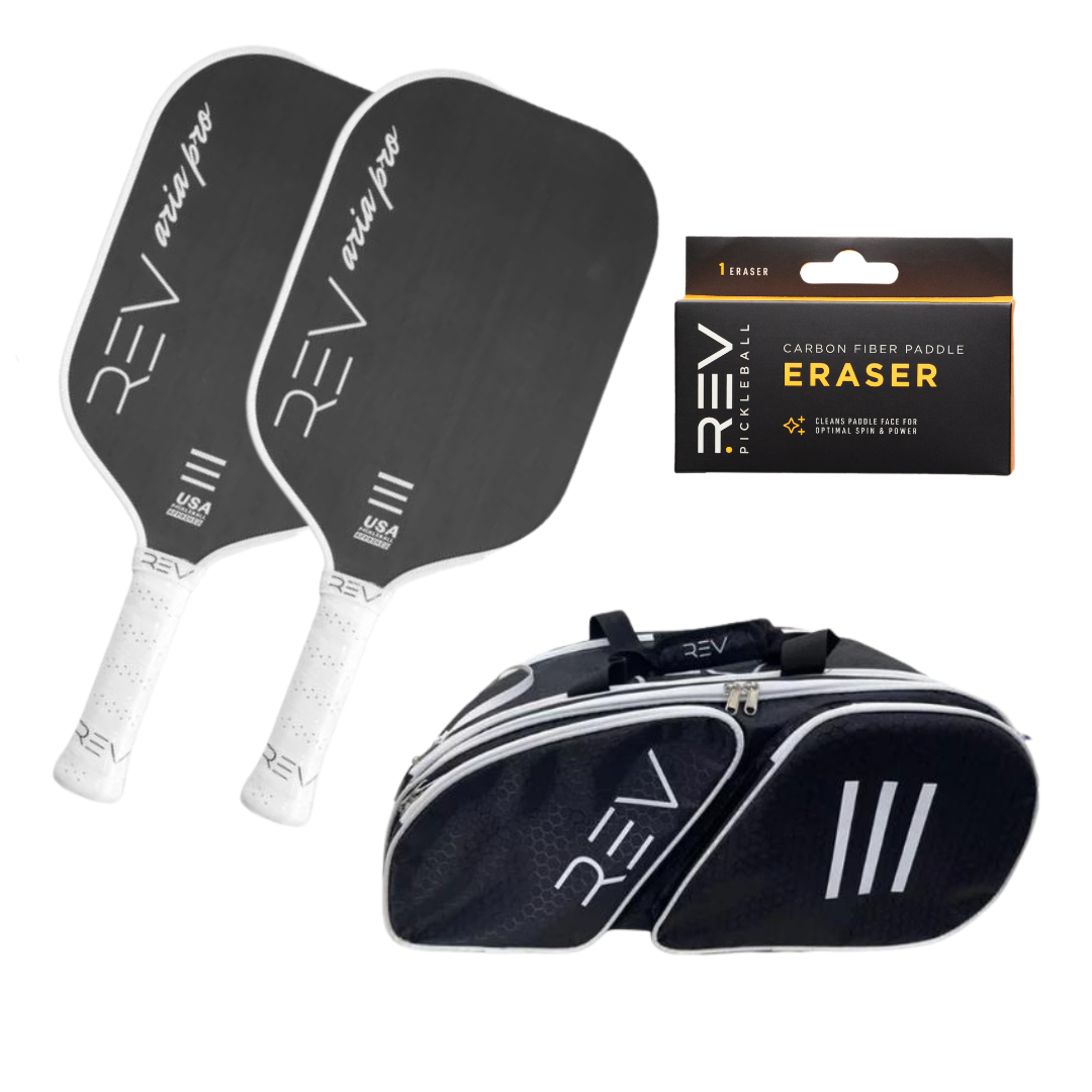 The REV Pickleball Professional - Mix & Match - Bundle for 2 includes two black "REV Aria Pro" paddles with white handles, a black and white paddle bag, and a packaged Carbon Fiber Paddle Eraser cleaning accessory.