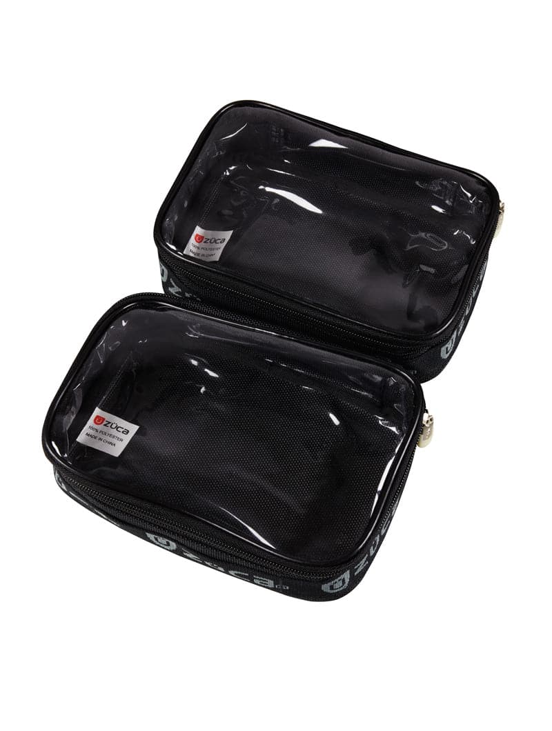 Two empty ZUCA Mini Utility Pouch Duo pouches are stacked. Each features a clear vinyl top, black fabric sides, gold zippers, visible inner labels, and white text along the edges for organized storage.