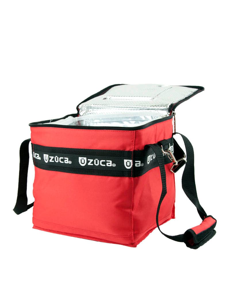 A red ZUCA Cooler insulated bag features a black adjustable shoulder strap, an open lid revealing a shiny silver cooling interior, and the ZUCA logo printed repeatedly on a black band around the bag.