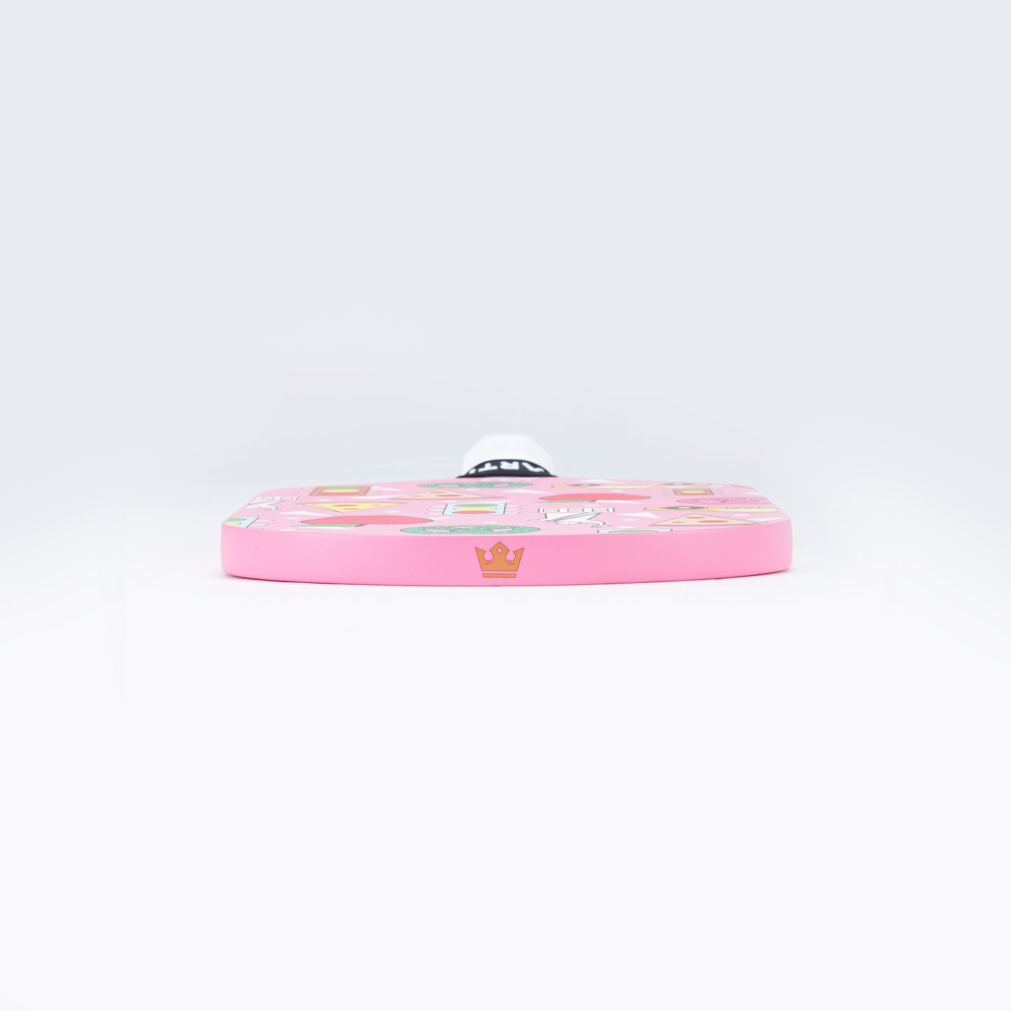 The ARTI Carbon Fiber "NEW YORK" Paddle by ARTI is shown from the edge, displaying a pink surface with vibrant cartoon-style graphics—stars, crowns, and playful shapes—taking inspiration from New York pickleball paddle designs.