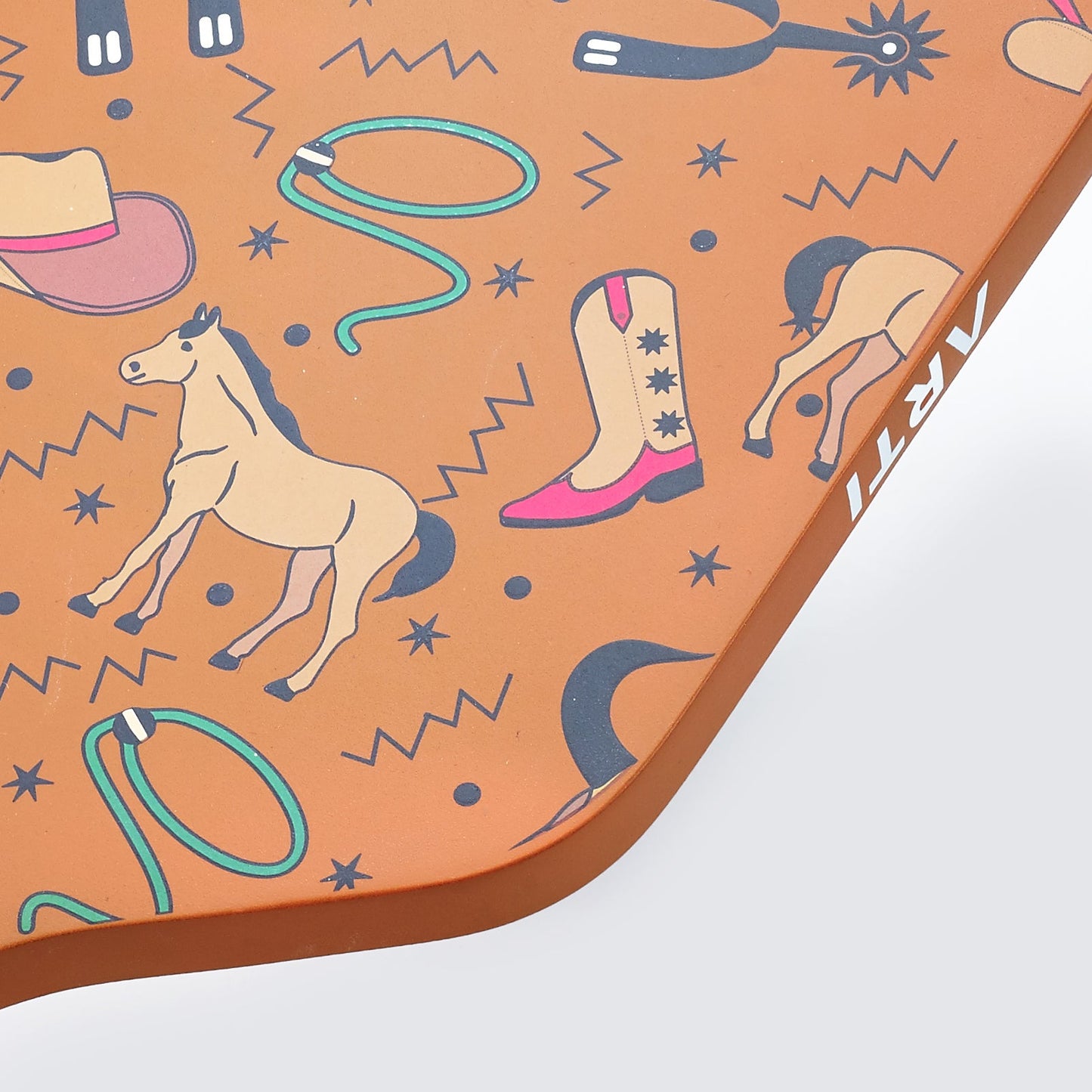 A close-up shows the ARTI Carbon Fiber "TEXAS" Paddle, decorated with Western illustrations—horses, cowboy boots, lassos, black stars, zigzags. “ARTI” in white curves on the edge of this USAPA approved paddle adds unique flair.