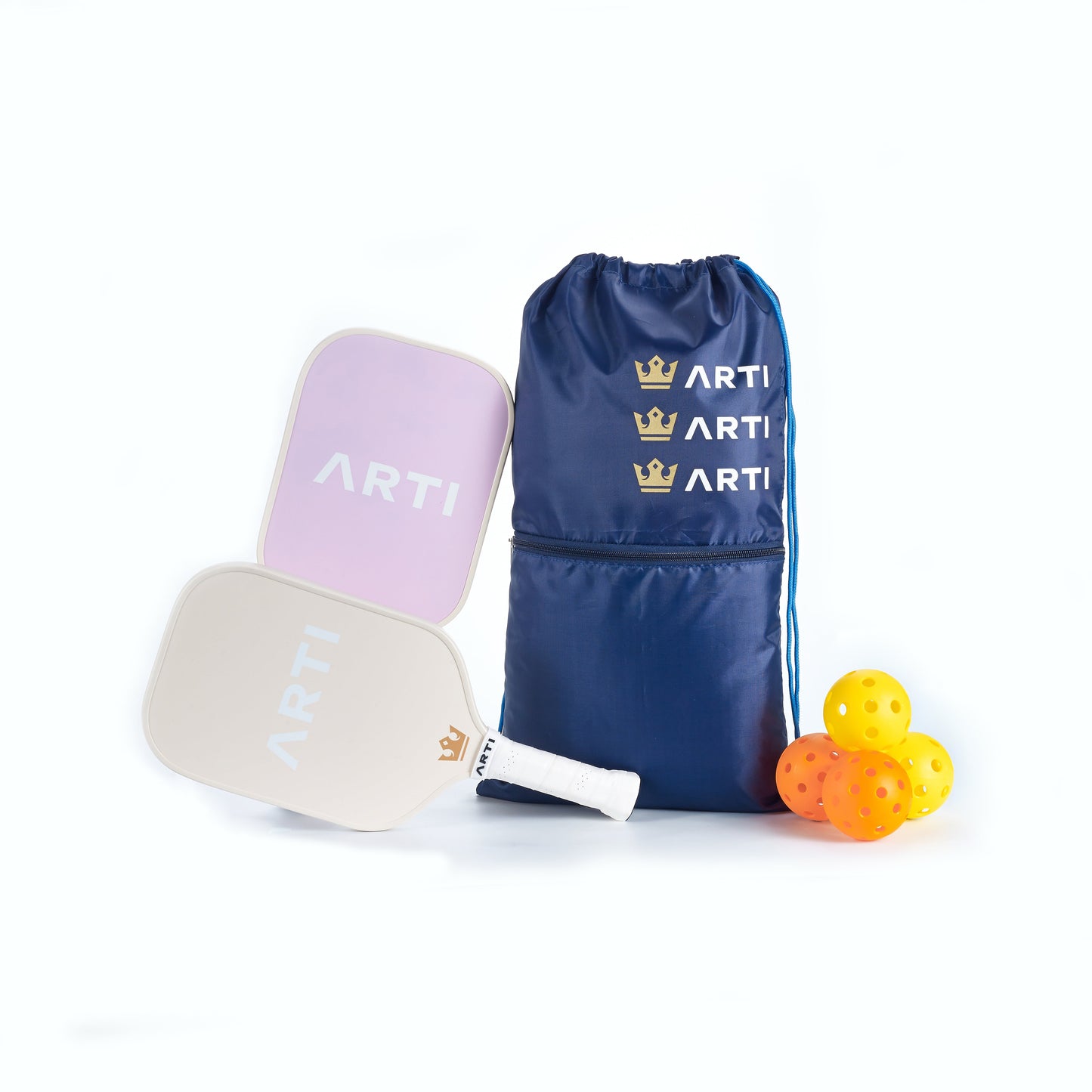 The ARTI Fiberglass "Dogs & Giraffes" Pickleball Paddle Set includes two USAPA approved paddles (pink and white), a navy blue ARTI drawstring bag with a gold crown logo, and four yellow perforated pickleballs.