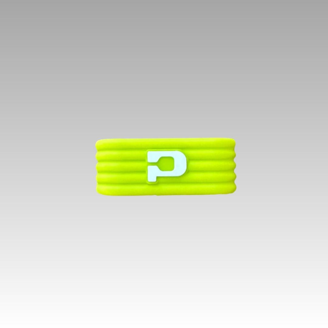 The Playly Store Pickleball Paddle Icon Grip Band is a bright yellow silicone wristband with four grooves and a raised white “P,” shown on a smooth gray background—ideal for pickleball enthusiasts.