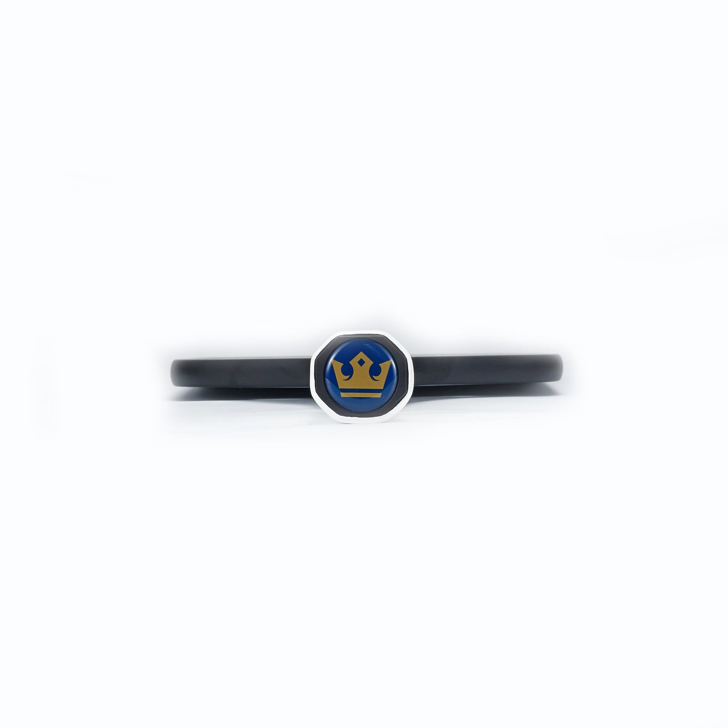 A black wristband with a silver hexagon emblem featuring ARTI's blue background and yellow crown, echoing the style of ARTI’s Carbon Fiber "MASTERY ELITE 1.0" Paddle. Set against a plain white background.