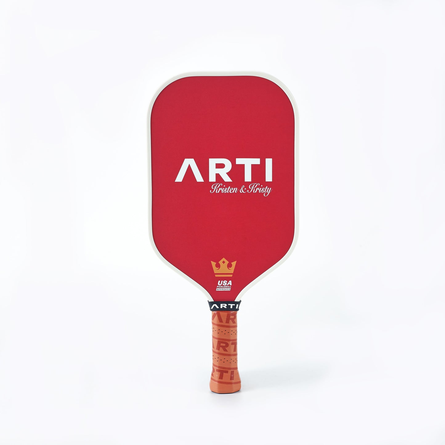 The ARTI Carbon Fiber Kristen&Kristy "X-MAS" Paddle features a bold white ARTI logo, cursive “Kristen & Kristy,” a gold crown, USA Pickleball text, and an orange grip with ARTI branding. USAPA approved.