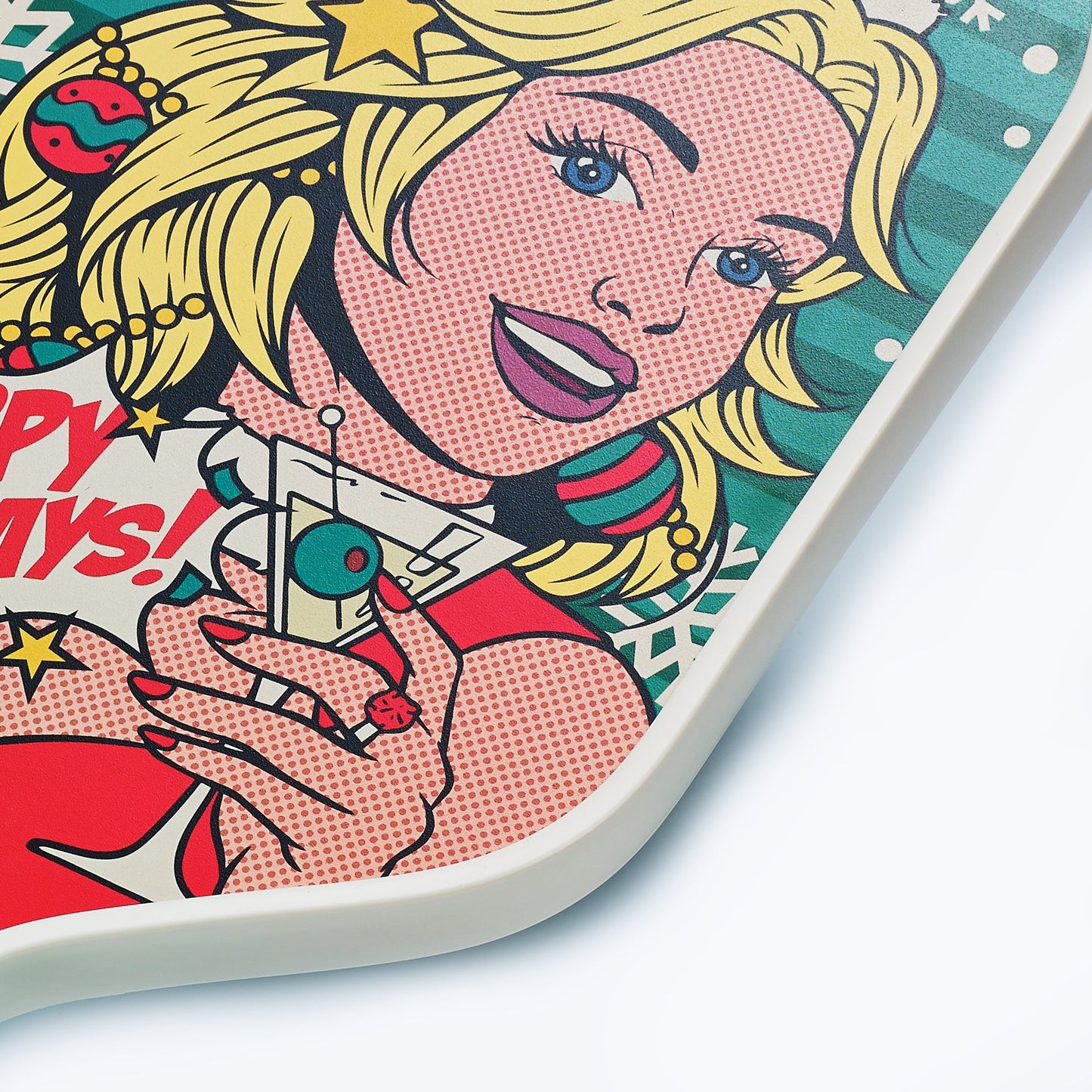 A close-up of the ARTI Carbon Fiber Kristen&Kristy "Happy Holidays" Paddle by ARTI shows a pop art blonde in red holding an ornament, with festive ornaments, stars, and snowflakes, plus “HAPPY DAYS!” in red letters on the background.