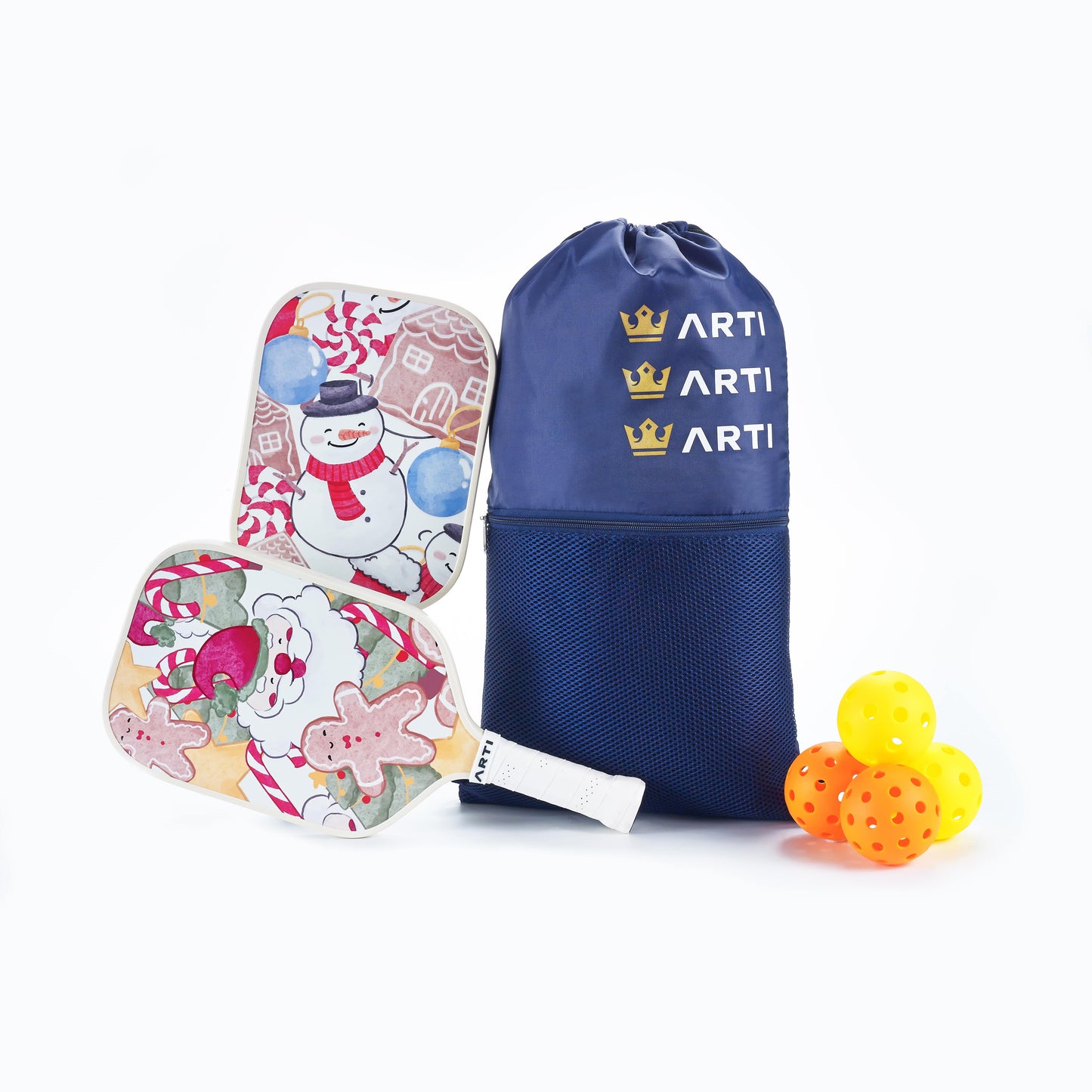 The ARTI Fiberglass "Christmas Edition" Pickleball Paddle set features two festive paddles—one with a snowman, one with gingerbread cookies—plus a blue ARTI bag and three yellow balls, making a delightful holiday set on a white background.