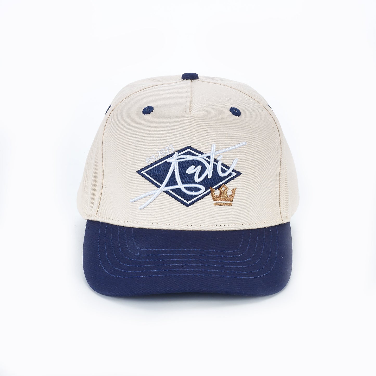 The ARTI Throwback Classic Rope Hat by ARTI features a beige crown, navy blue brim and button, and a diamond-shaped blue patch on the front with white “Arte”, “08-2013”, and a small gold crown embroidered.