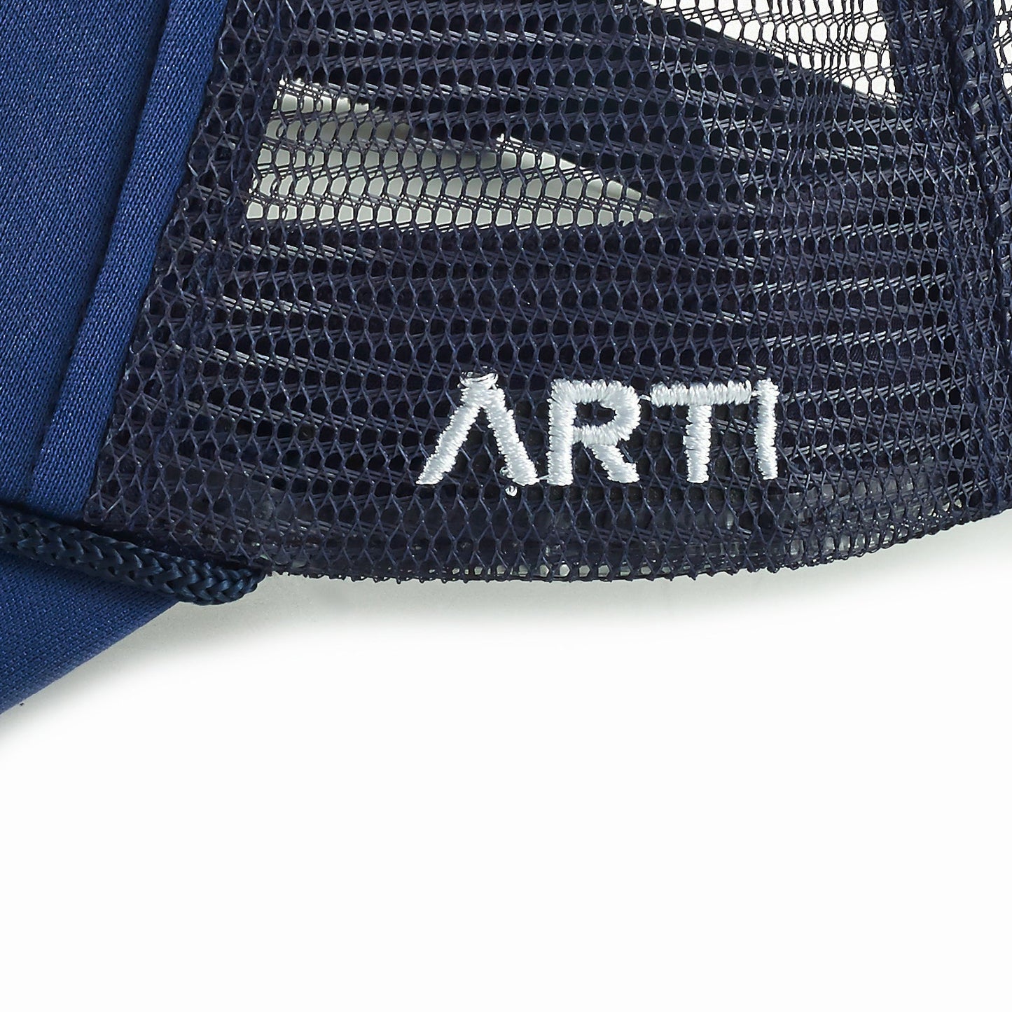 Close-up of the Ain't No Party Like ARTI Trucker Hat by ARTI, featuring "ARTI" embroidered in white on the navy mesh. The lightweight sports hat has a curved brim, shown partially on the left against a white background.
