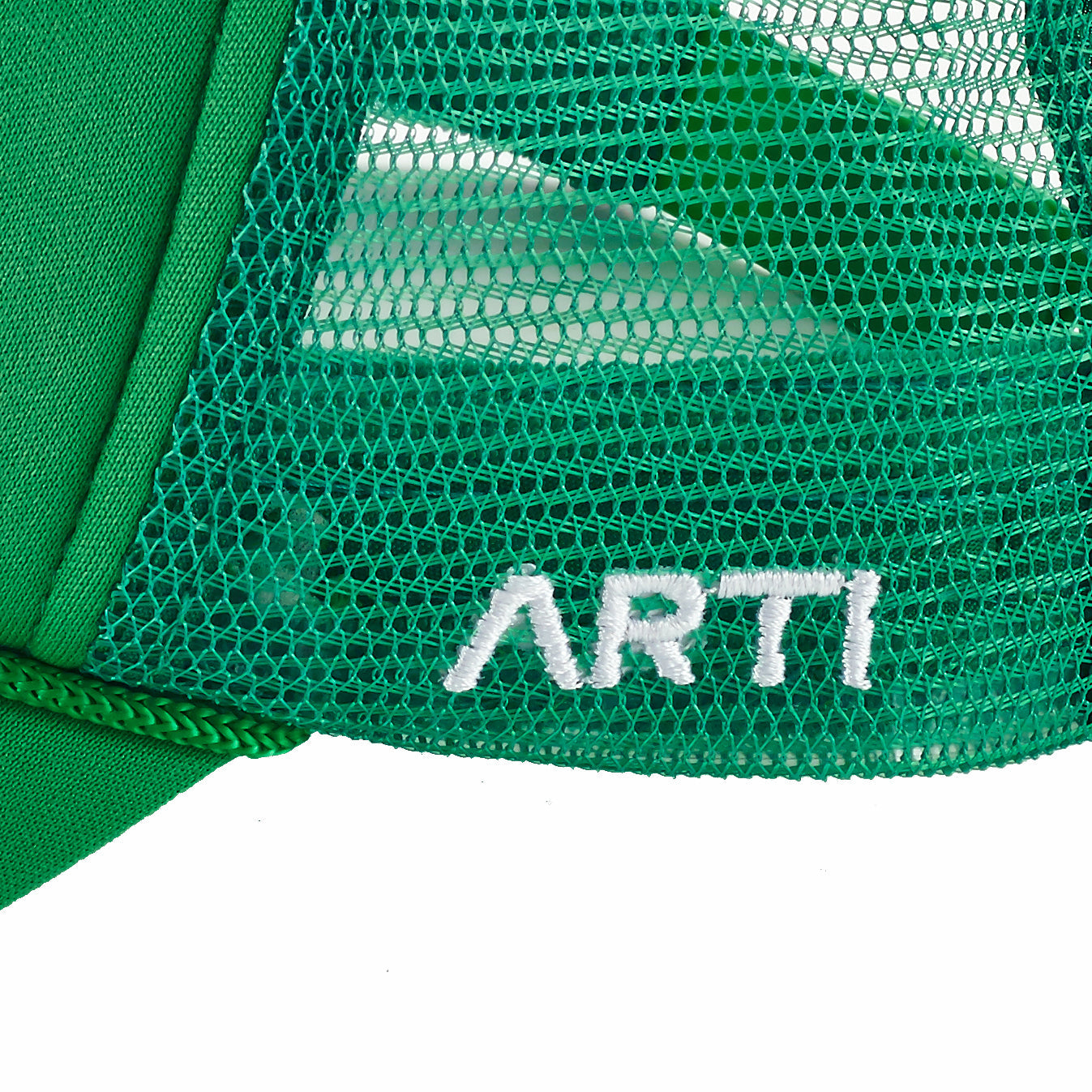 Close-up of the Ain't No Party Like ARTI Trucker Hat by ARTI, featuring green mesh, a solid green brim, and white embroidered "ARTI" on the mesh section with visible stitching and textured lightweight sports fabric.