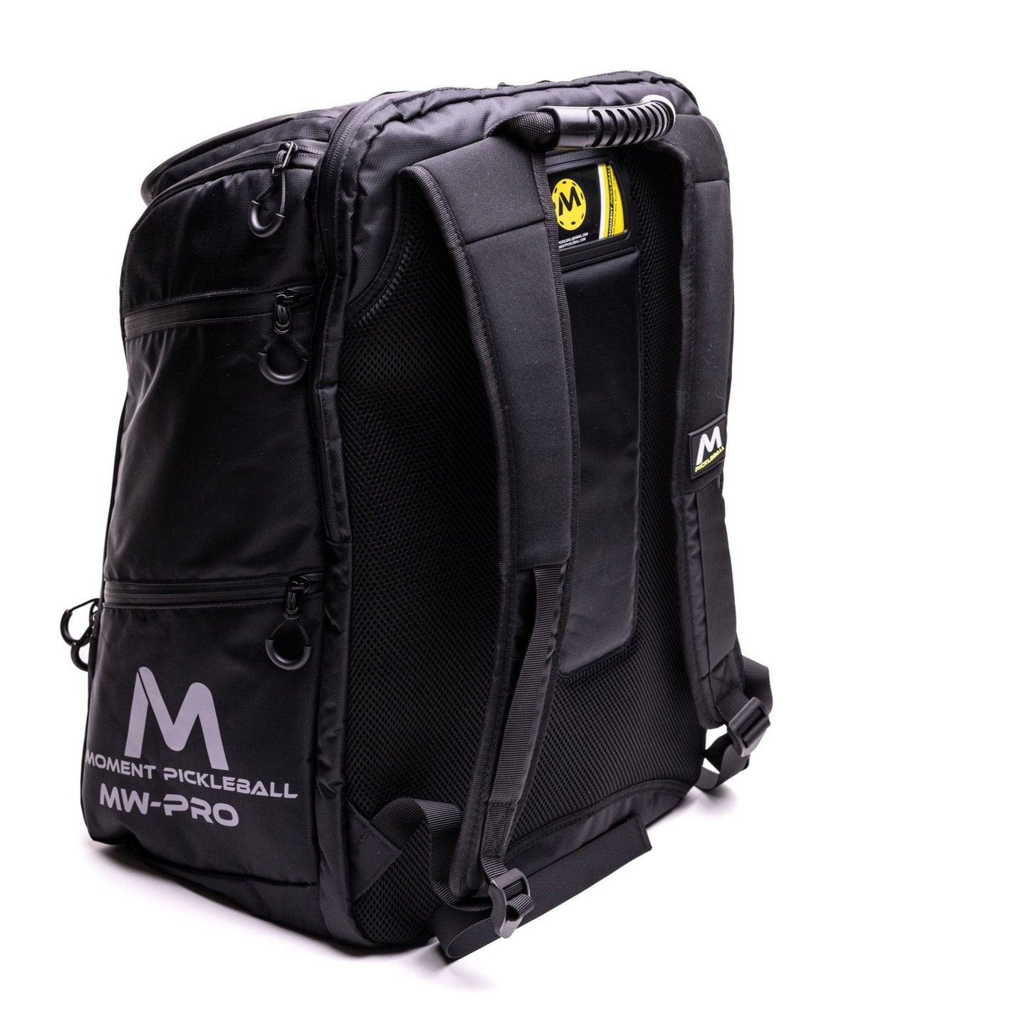 The Moment Pickleball MW-PRO Bag / Travel Bag in Black/Silver stands upright, displaying padded shoulder straps, mesh back support, a ridged handle, side zippered pockets, and a white logo on the lower pocket—ideal for all your pickleball gear.