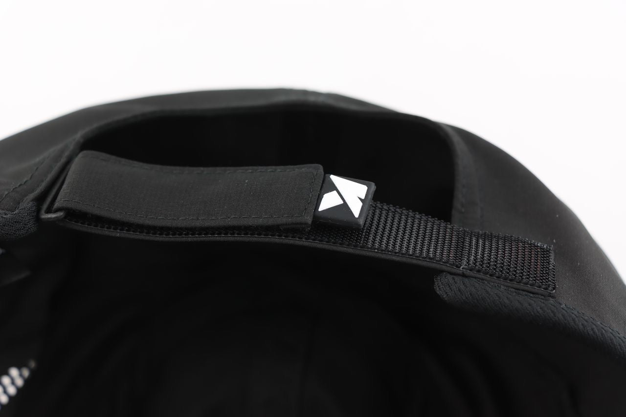 Close-up of the inside back of a KONDOR PICKLEBALL Game Day Ready Quik Dry Hat, featuring an adjustable hook-and-loop strap with a small black tag displaying a white geometric logo. The background is plain white.
