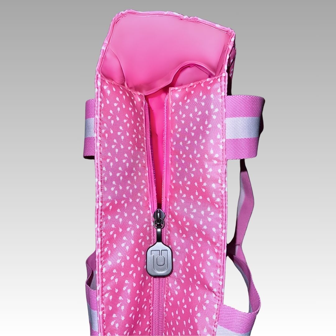 A close-up of the Lulu Pickleball Tote by Playly Store, featuring pink fabric with white polka dots, a central zipper, and light pink and white striped straps, shown against a plain gray gradient background.