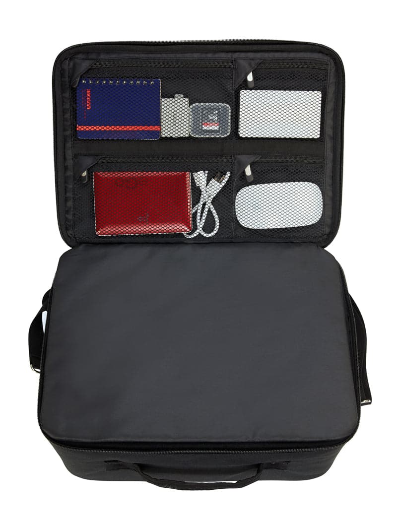 An open black ZUCA Tech Case with mesh zippered pockets in the lid holds a blue notebook, gray adapter, white device, red passport holder, and white charging cable. Its main compartment is empty, with side handles and padded dividers.