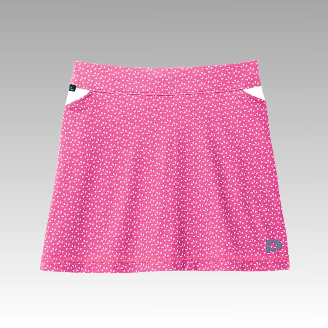 The Playly Store Sammy Skort 2.0 is a pink A-line pickleball skort with a white heart pattern, CoolFlow moisture-wicking fabric, wide waistband, small white hip accents, and blue embroidered logo on the lower right. Set on a neutral gray gradient background.