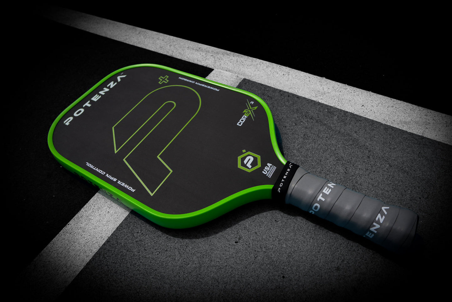 The Potenza Pickleball P+ PowerSpin Carbon COREx3 paddle, featuring a neon green elongated face, rests on the court ready for the next match.