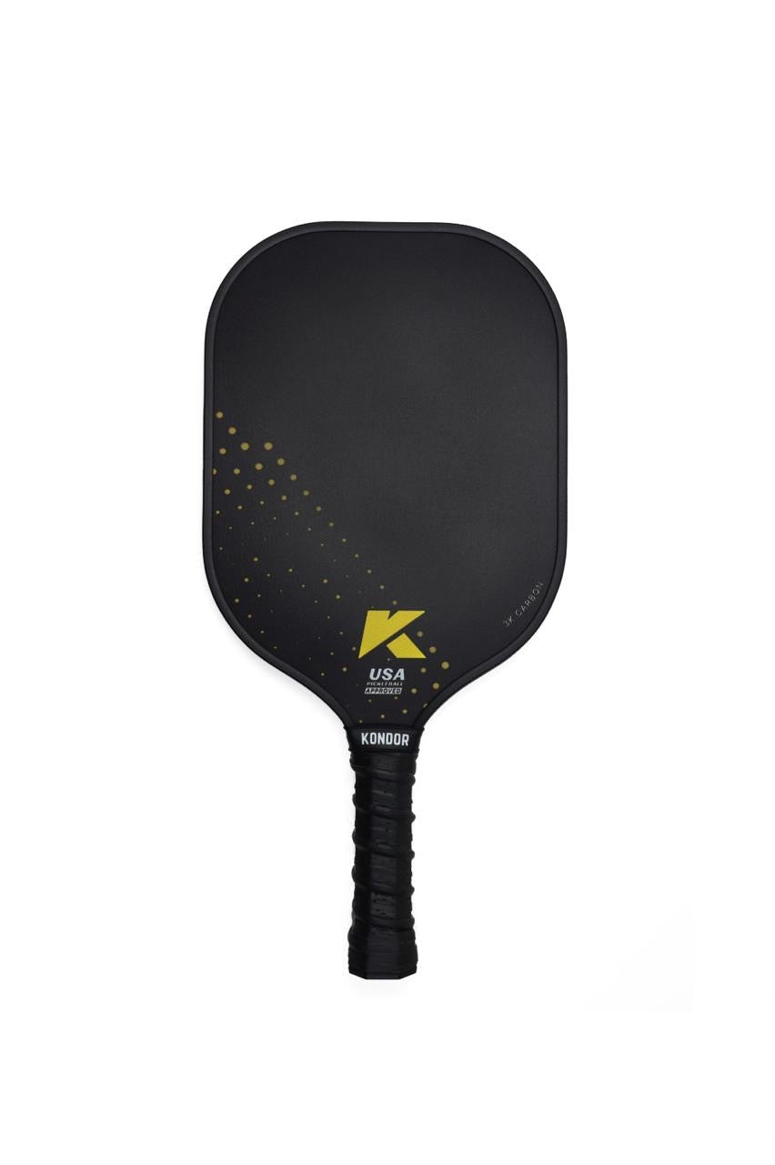 The KONDOR PICKLEBALL DUNE 3K Carbon Pickleball Paddle has a black 3K carbon textured face with gold diagonal dots and a gold K logo, "USA Pickleball Approved" below, plus a ridged black EVA comfort grip. Shown on a white background.