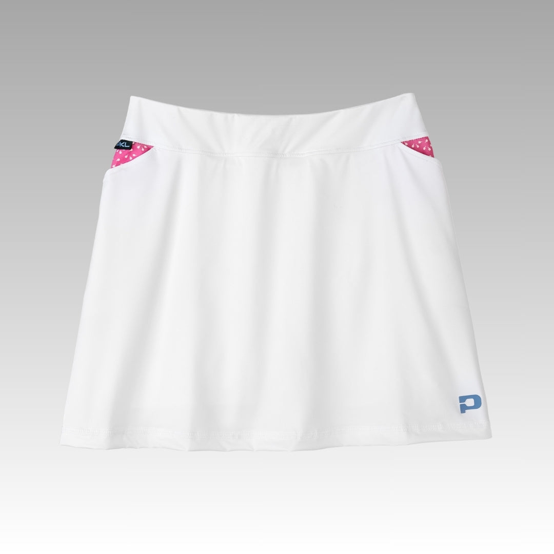 The Sammy Skort 2.0 by Playly Store is a white athletic high-waisted skort with pink polka-dot pocket linings, a blue P logo on the right hem, and a smooth CoolFlow fabric design, shown on a gradient gray-to-white background.