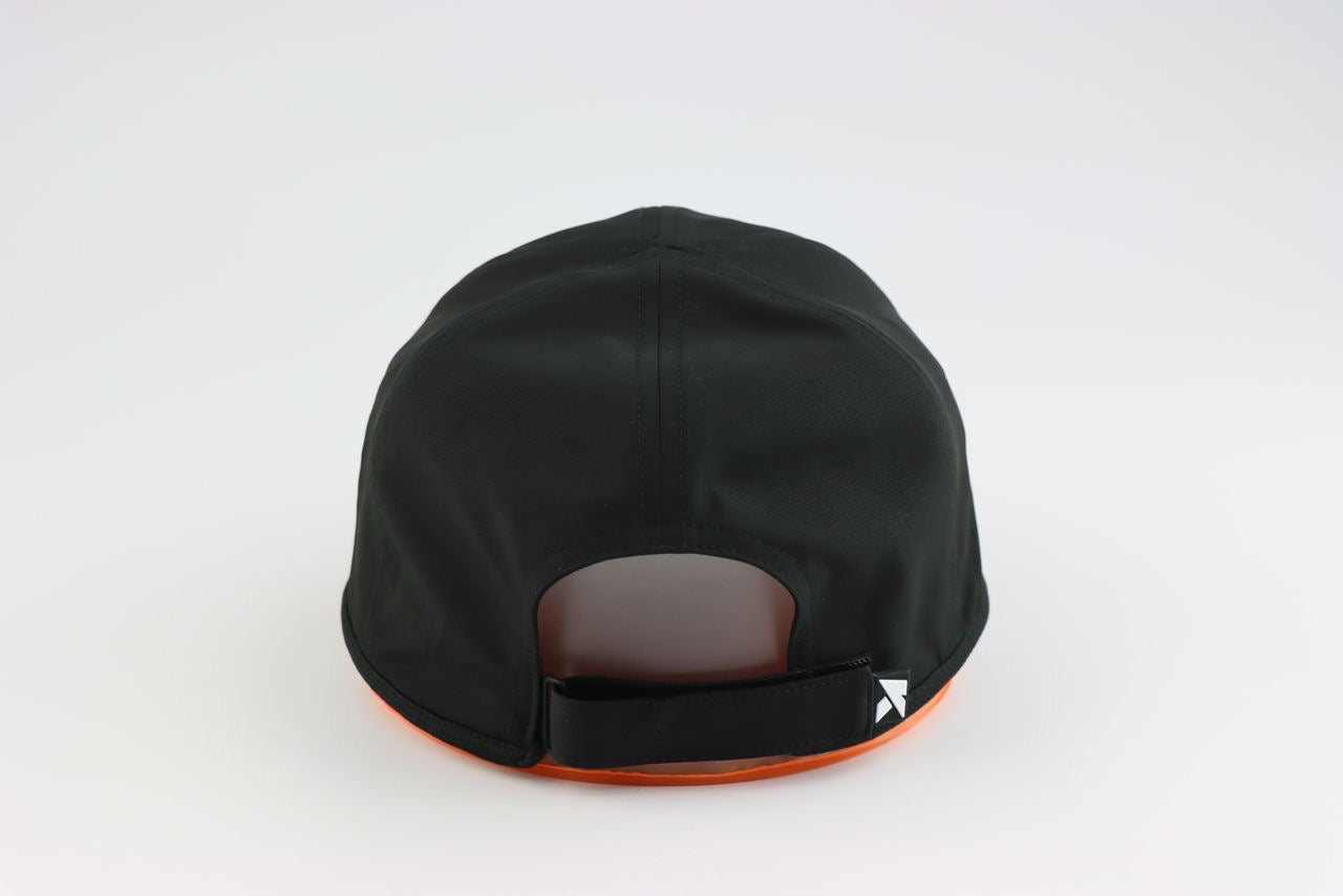 A black KONDOR PICKLEBALL Game Day Ready Quik Dry Hat viewed from the back, featuring an athletic brim with a touch of orange and an adjustable velcro strap with a small geometric white logo, set against a plain white background.