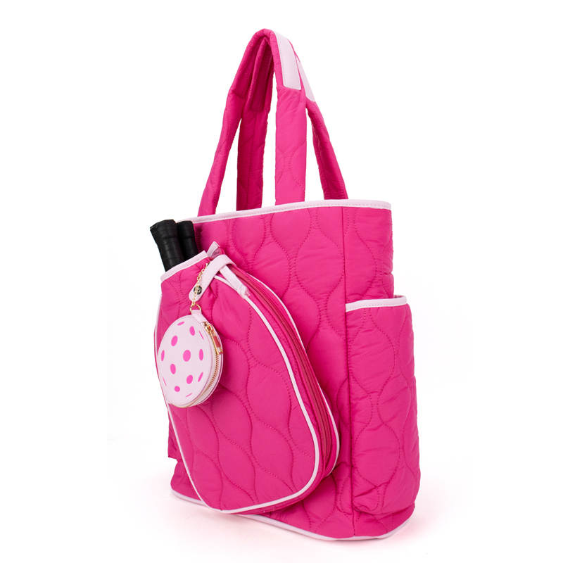 The Queen of the Court Fifth Ave Pickleball Convertible Tote Bag/Backpack features bright pink quilted fabric, white trim, two black handles, multiple pockets, and a front pocket with a pink polka dot ball keychain.