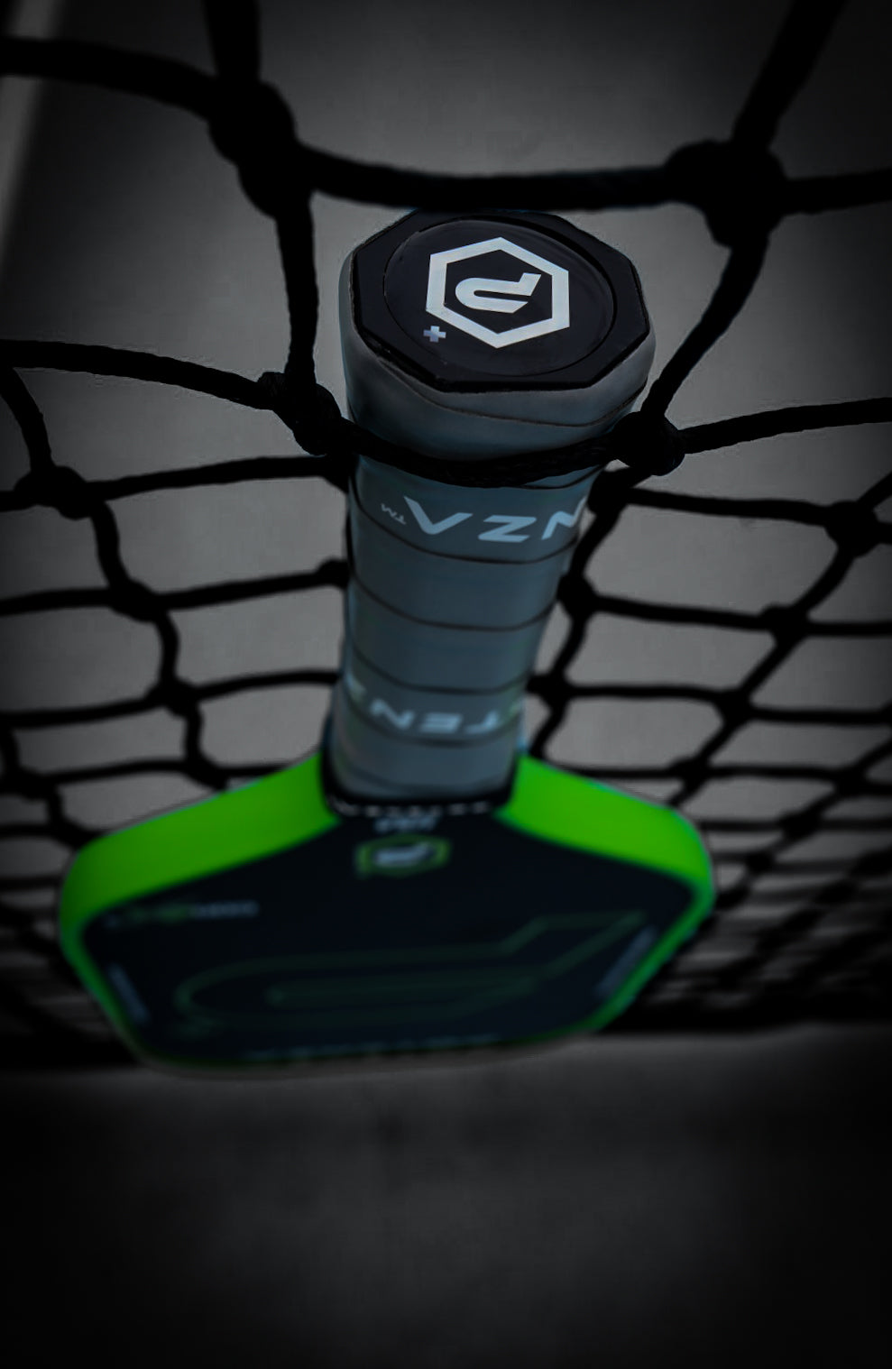 The Potenza Pickleball P+ PowerSpin Carbon COREx3 (Neon Green) paddle, featuring bold black and neon green angular designs and a geometric logo on the grip, stands vertically with its handle resting on a black net.
