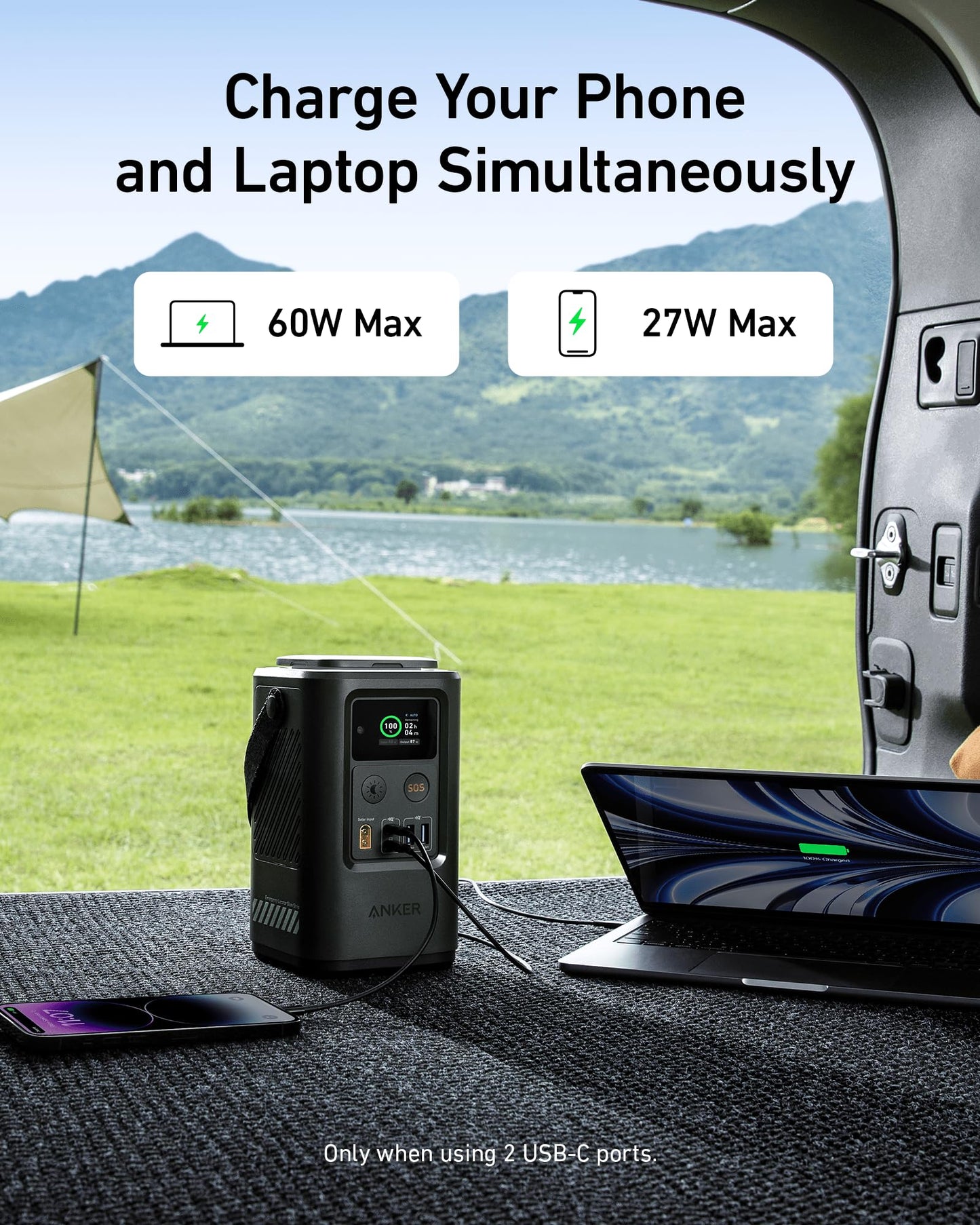 An Anker 548 Power Bank (PowerCore Reserve 192Wh) sits in a car trunk, charging a smartphone (60W Max) and laptop (27W Max). Perfect for emergencies, with a tent and lake visible outside.