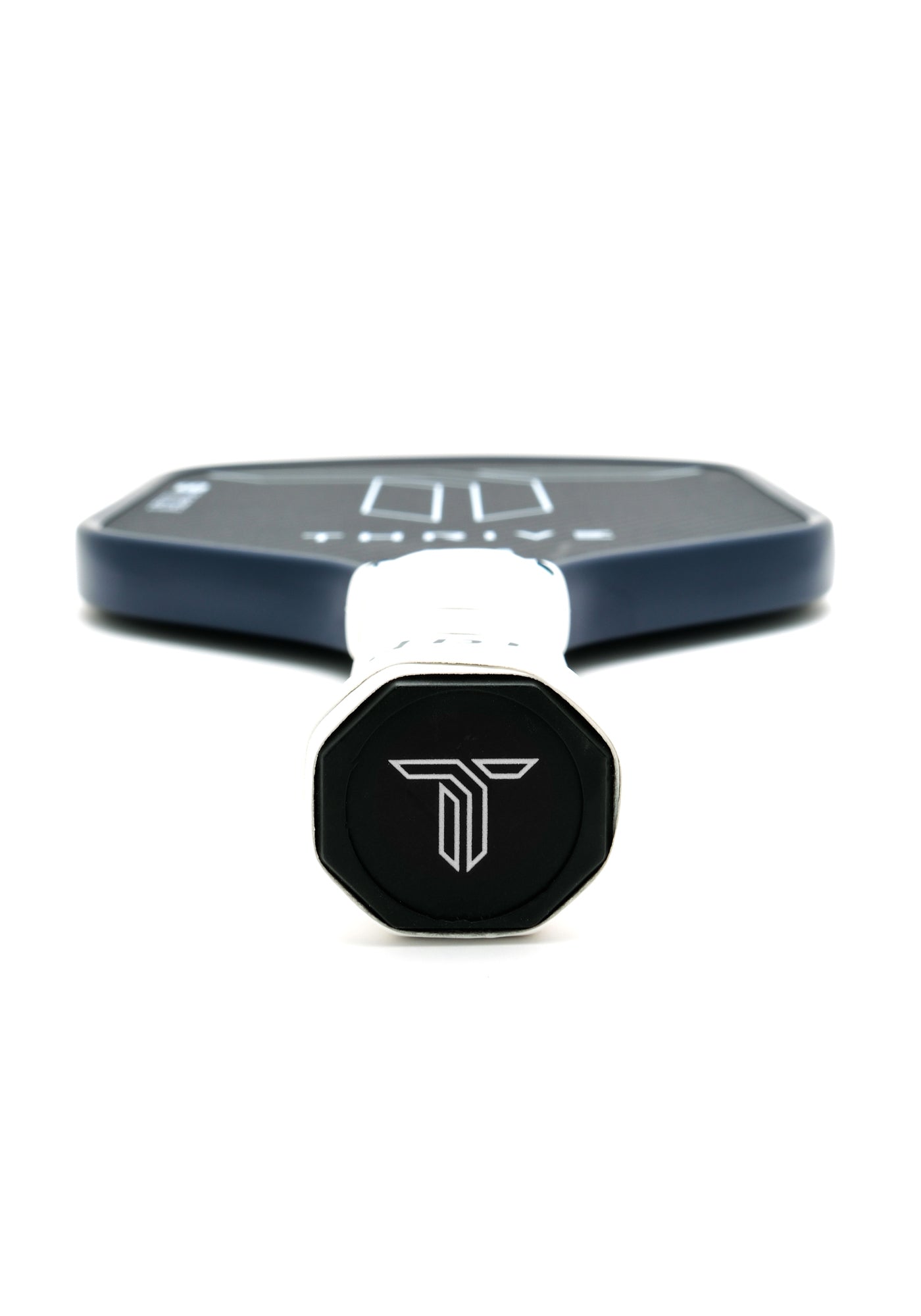 Close-up of the Thrive Pickleball AZUL 16mm (POWER SERIES) paddle, handle facing the camera with a white “T” logo on black cap. Paddle includes lead weights, key chain, and weight card. Paddle surface blurred against white background.