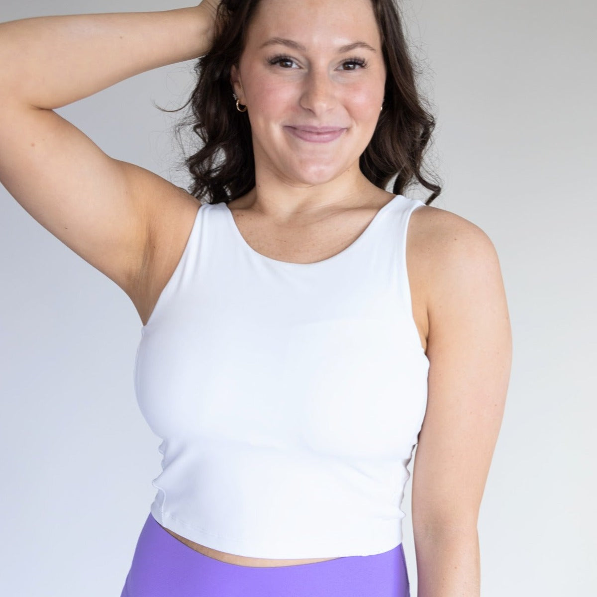 A woman wears the DYM Athletics Flex High Neck Bra with scoop back (A-D cups, medium support), paired with purple pants.