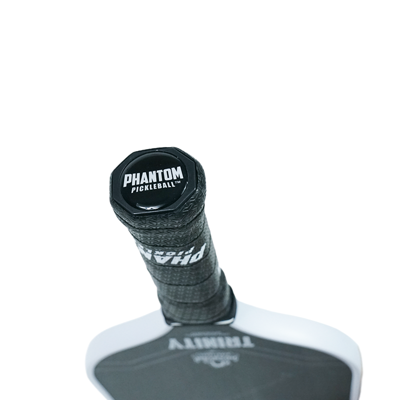 Close-up of the Phantom TRINITY 14MM T700 Raw Carbon Fiber Thermoformed Pro Pickleball Paddle by Phantom Pickleball, featuring a hexagonal end cap with white branding, textured grip tape, and its raw carbon fiber surface.