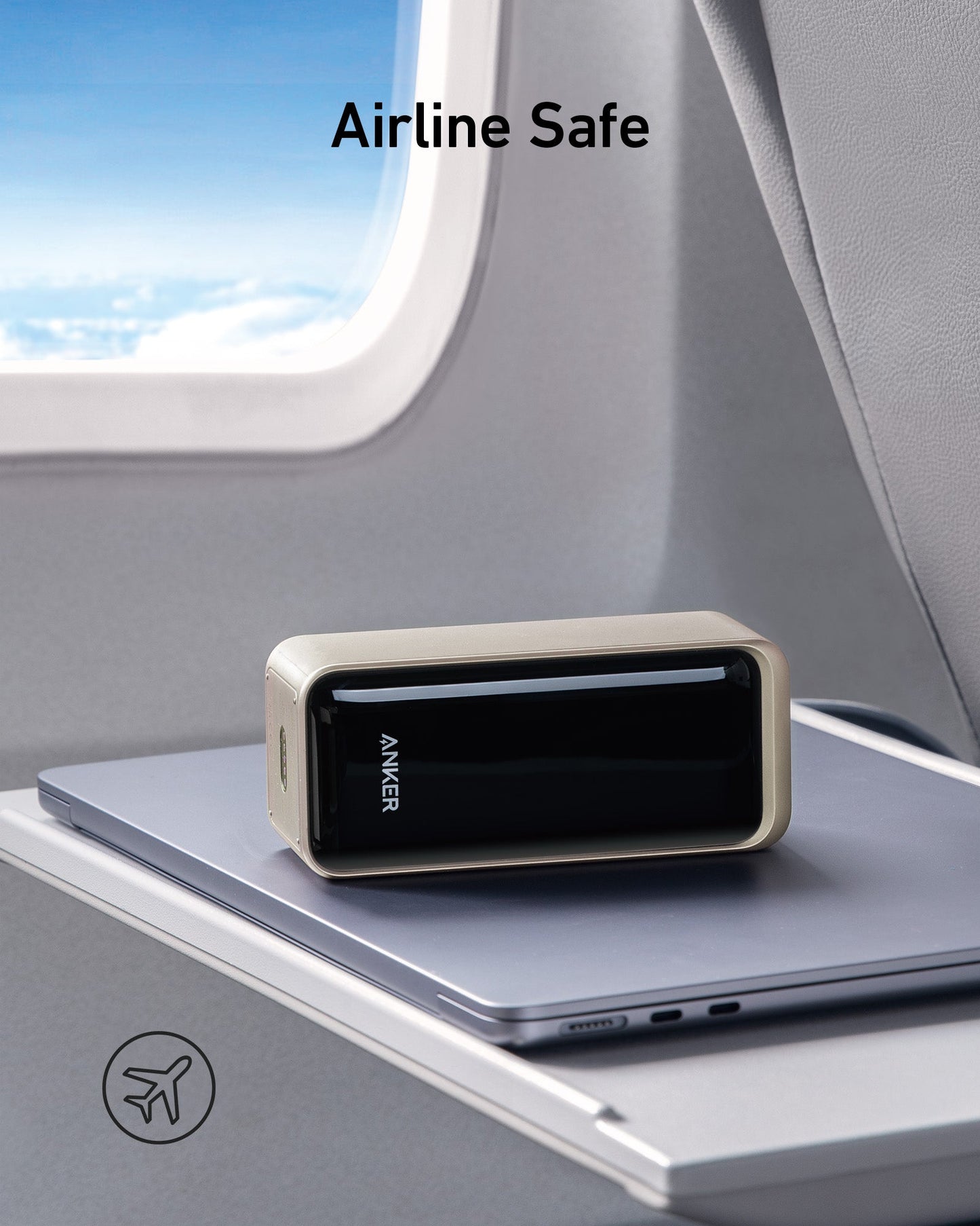 An Anker Prime Power Bank (20K, 200W) sits on a closed laptop atop an airplane tray table. Through the window, a blue sky with clouds is visible. "Airline Safe" appears above with an airplane icon in the lower left corner. Brand: Anker.