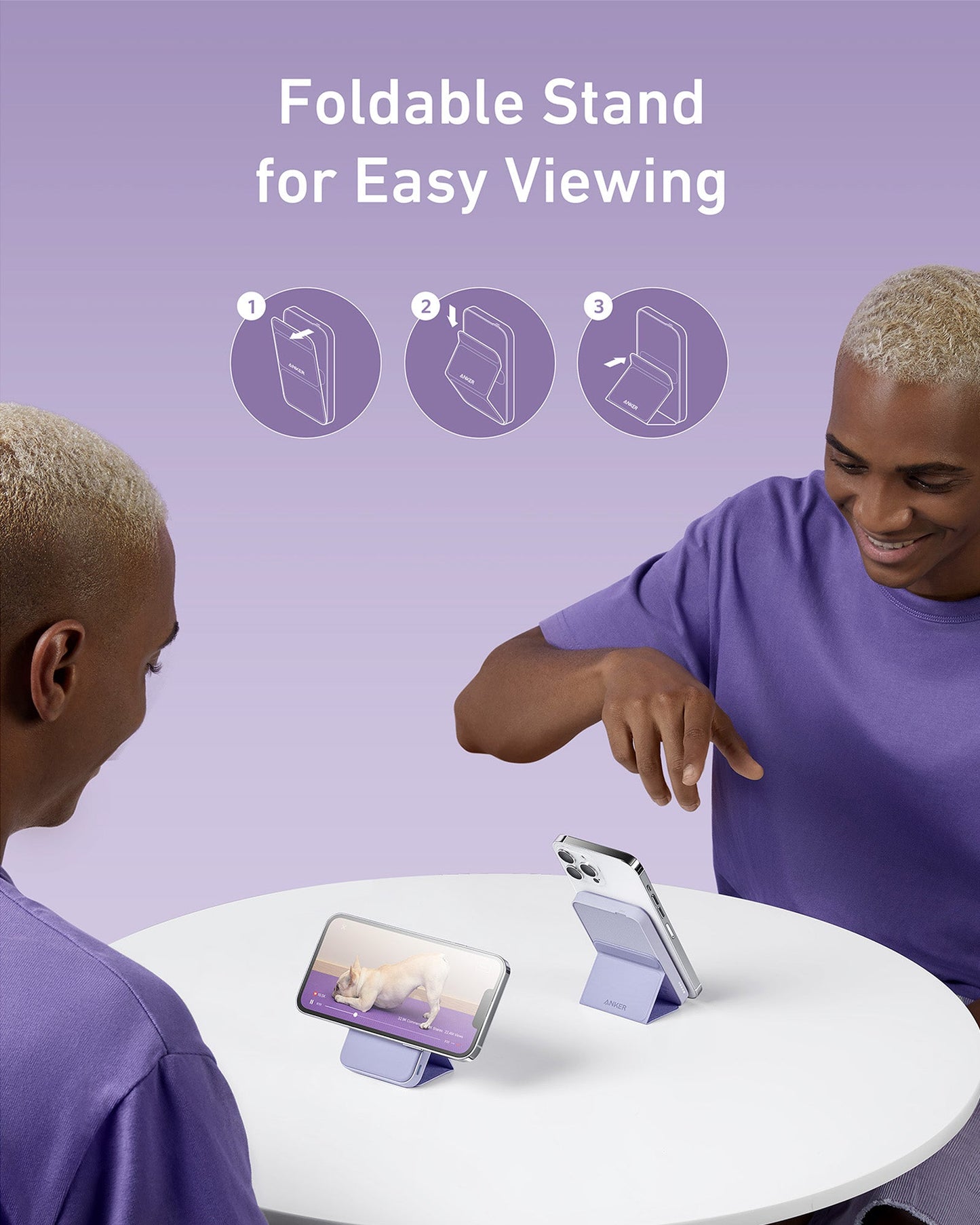 A person in a purple shirt smiles at a round white table, using the Anker 622 Magnetic Battery (MagGo) as a foldable stand to hold their phone upright. Another phone lies horizontally. Above, text reads “Anker: Foldable Stand for Easy Viewing” with simple instructions shown.