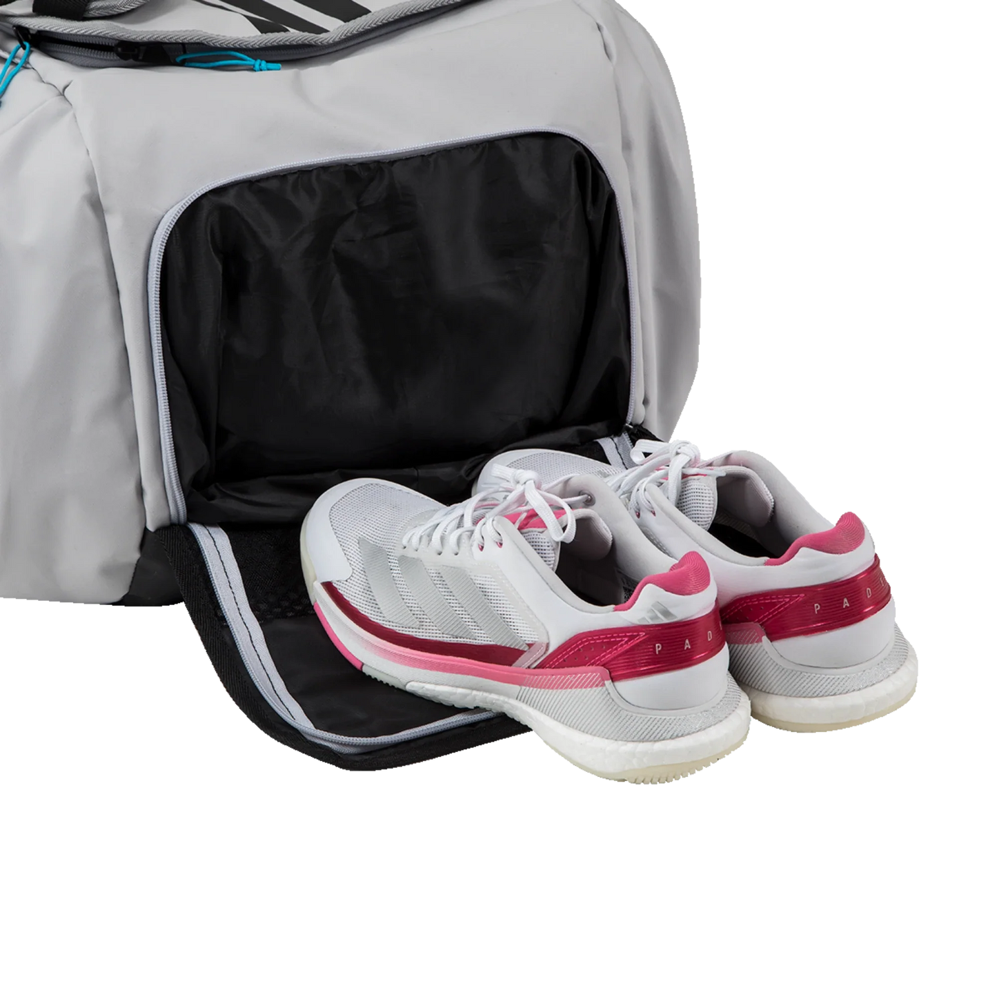 A pair of white athletic shoes with pink accents sit beside the Padel USA Adidas PROTOUR OFFWHITE Racket Bag 3.4, which has its ventilated bottom compartment unzipped to reveal a spacious black interior ready for shoe storage.