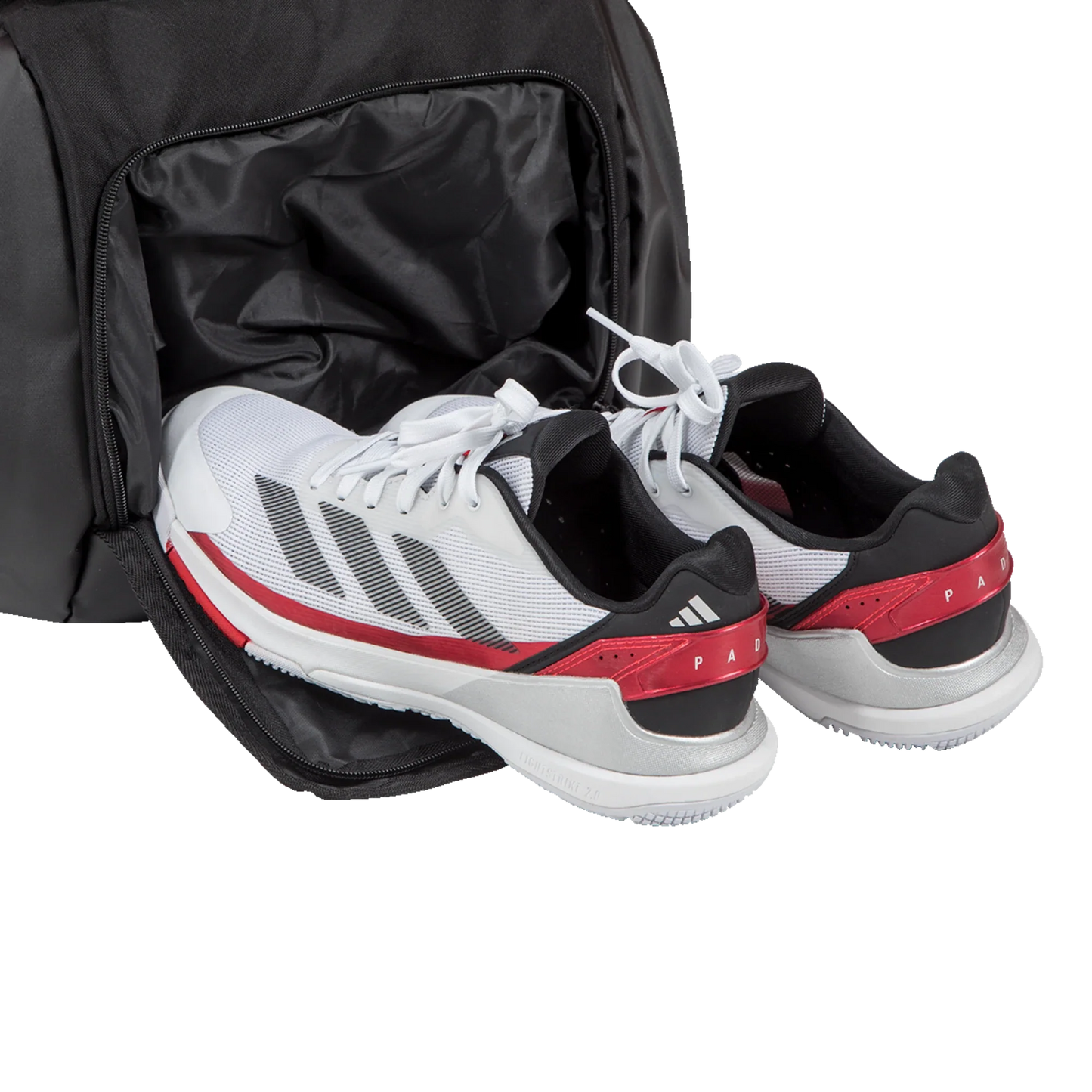 A pair of white sneakers with black and red accents are partially inside the ventilated shoe compartment of the spacious Padel USA Adidas TOUR BLACK Racket Bag 3.4, showing black stripes, visible laces, and a clean sporty look.