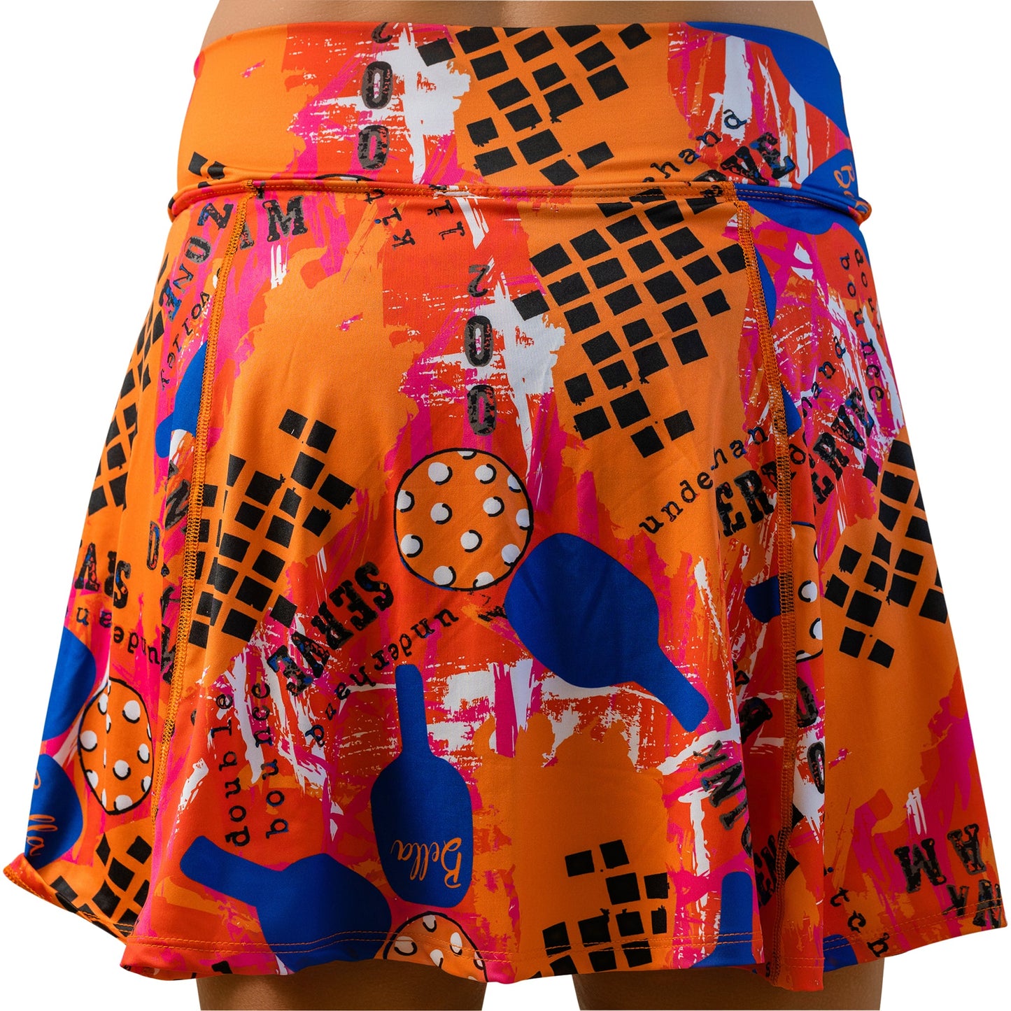 The Pickleball Bella PB Aline Skort Graffiti 3 features a vibrant abstract print with black grids, blue and orange paddles, polka-dotted balls, a slim orange waist belt, and built-in compression shorts for comfort on or off the court.