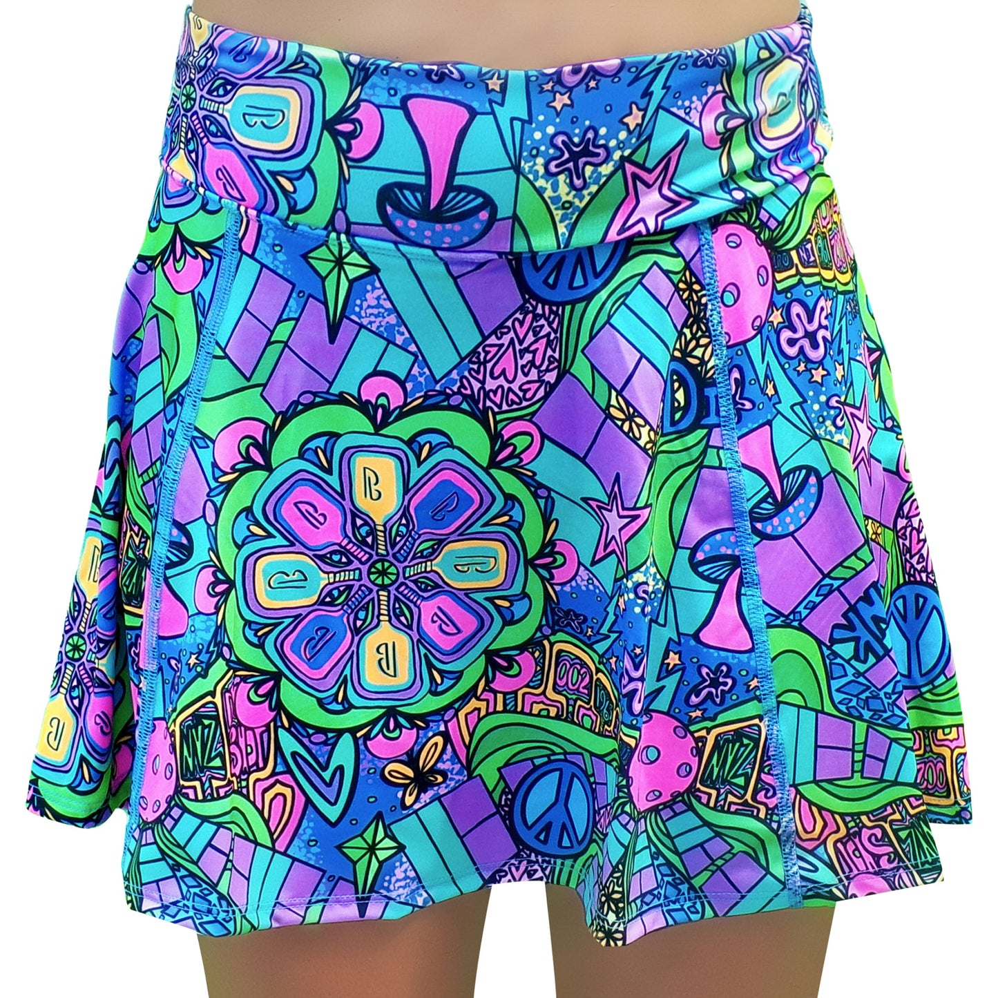 The PB Aline Skort Groovy by Pickleball Bella is a vibrant pickleball skirt with a psychedelic blue, green, pink, and purple print featuring peace signs, stars, flowers, and abstract shapes. Displayed on a mannequin torso.