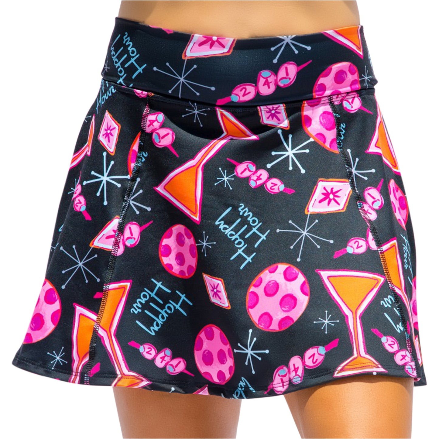 The Pickleball Bella PB Aline Skort Martini 2-4-1 Happy Hour, shown waist to upper thigh on a model, features a colorful pattern with pink martinis, polka-dotted balls, atomic starbursts, and “Happy Hour” text.