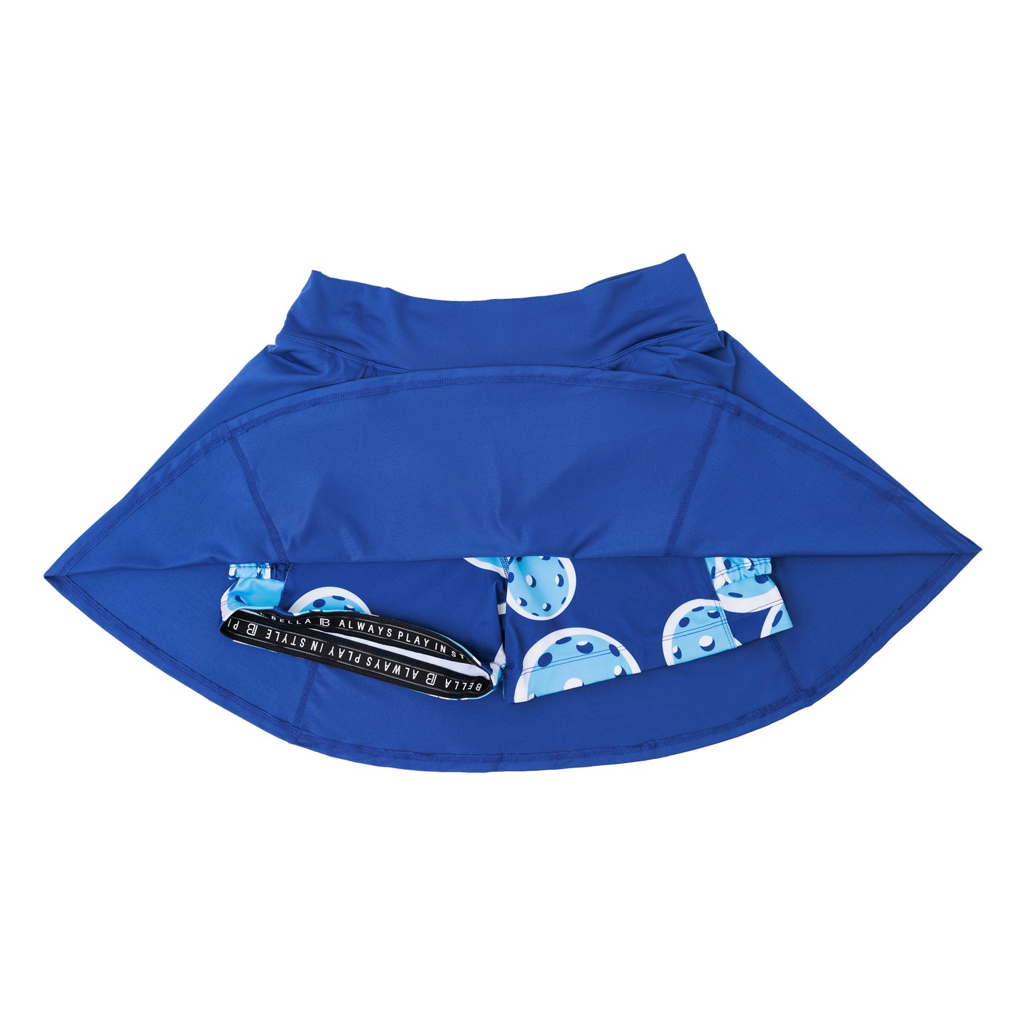 The Pickleball Bella PB Aline Skort Navy with Double Bounce is shown flipped up, revealing inner compression shorts with a playful pickleball paddle and ball print, plus a black-and-white “DINK & DRINK REPEAT” waistband.