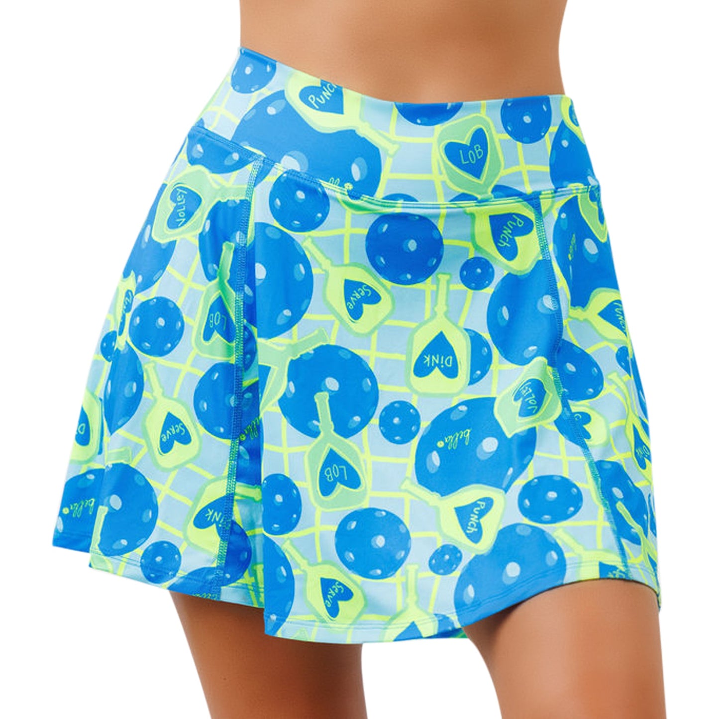 A close-up of a person wearing the Pickleball Bella PB Aline Skort Net Worth, a high-waisted blue and neon green athletic skirt with polka dots, hearts, playful text, built-in compression shorts, and a flared sporty style.